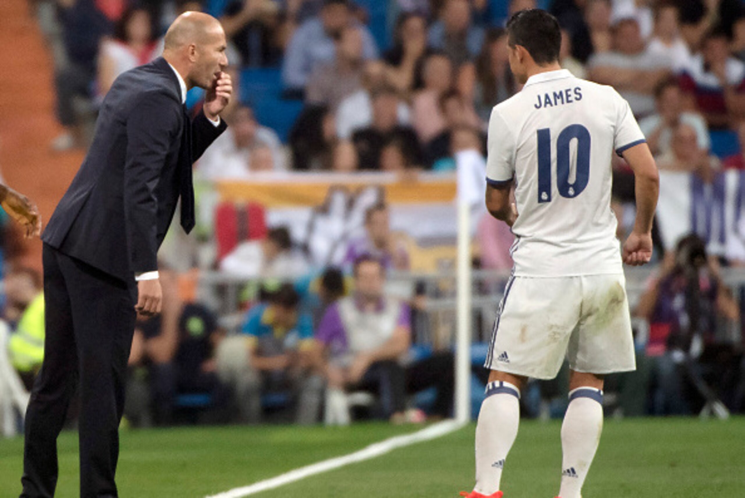 Real Madrid's French coach Zinedine Zidane (L) talks with Real Madrid's Colombian midfielder James Rodriguez during the Spanish league football match Real Madrid CF vs Villarreal CF at the Santiago Bernabeu stadium in Madrid on September 21, 2016. / AFP /