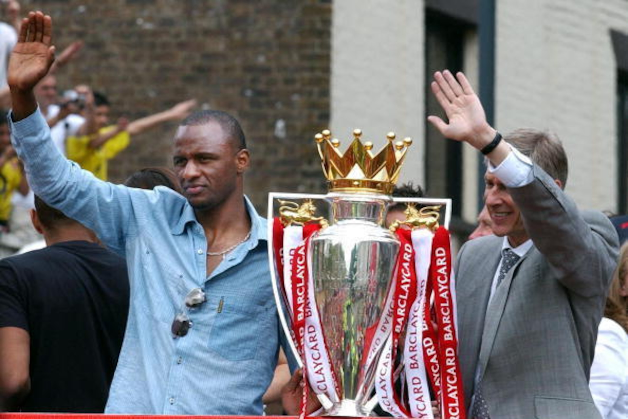 LONDON, UNITED KINGDOM:  Arsenal team captain Patrick Vieira (L) and manager Arsene Wenger wave from the open-top bus carrying the winners of the British Premier League Championship, Arsenal players and their families, on  its way to Islington Town Hall,1