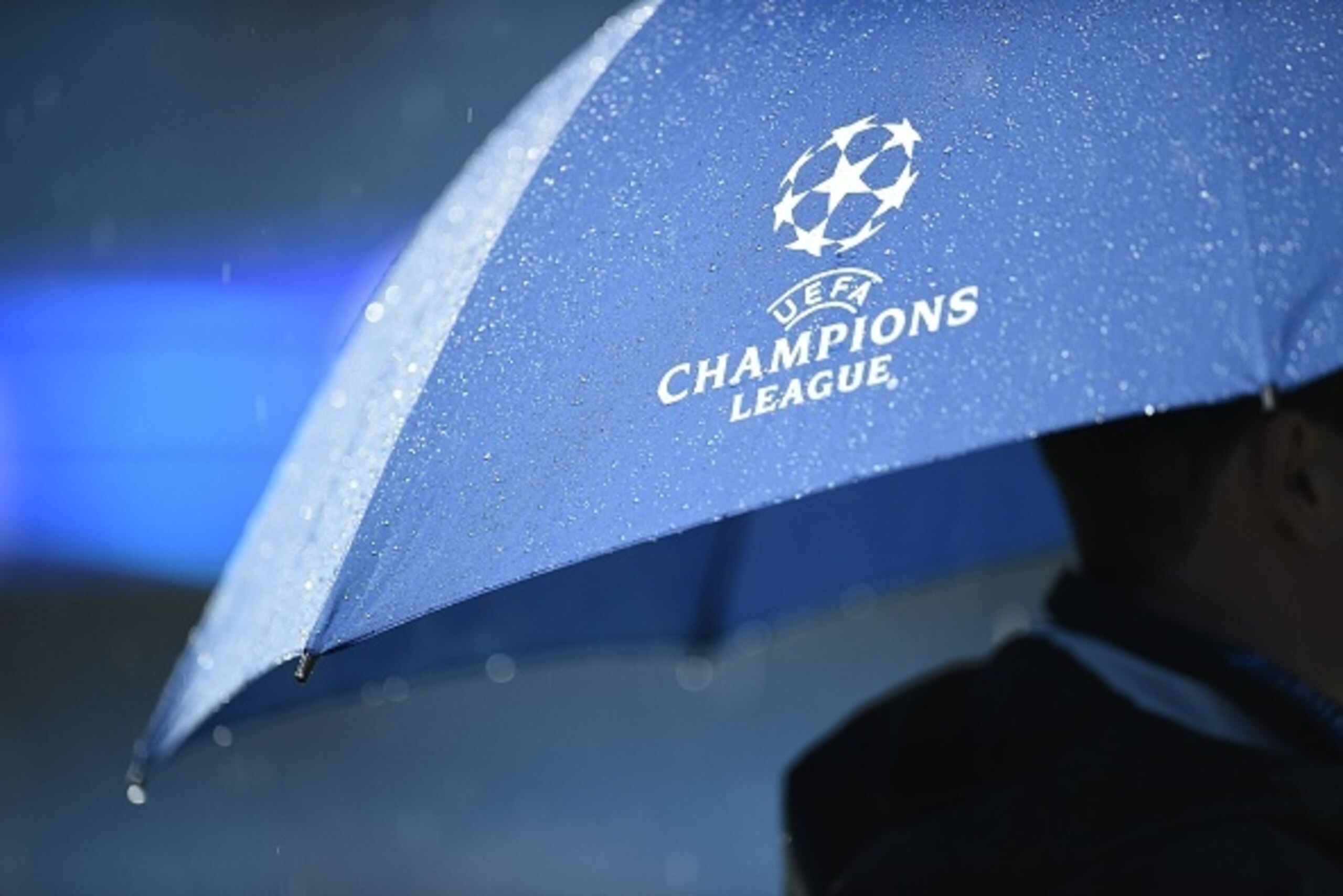 A match official shelters under an umbrella as heavy rain continues to pour ahead of the UEFA Champions League group C football match between Manchester City and Borussia Monchengladbach at the Etihad stadium in Manchester, northwest England, on September