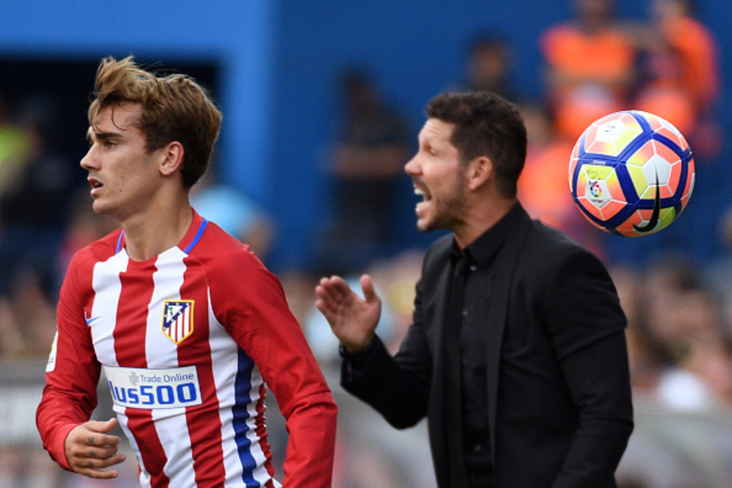 Atletico Madrid's French forward Antoine Griezmann (L) throws the ball beside Atletico Madrid's Argentinian coach Diego Simeone during the Spanish league football match Club Atletico de Madrid vs RC Deportivo de la Coruna at the Vicente Calderon stadium i