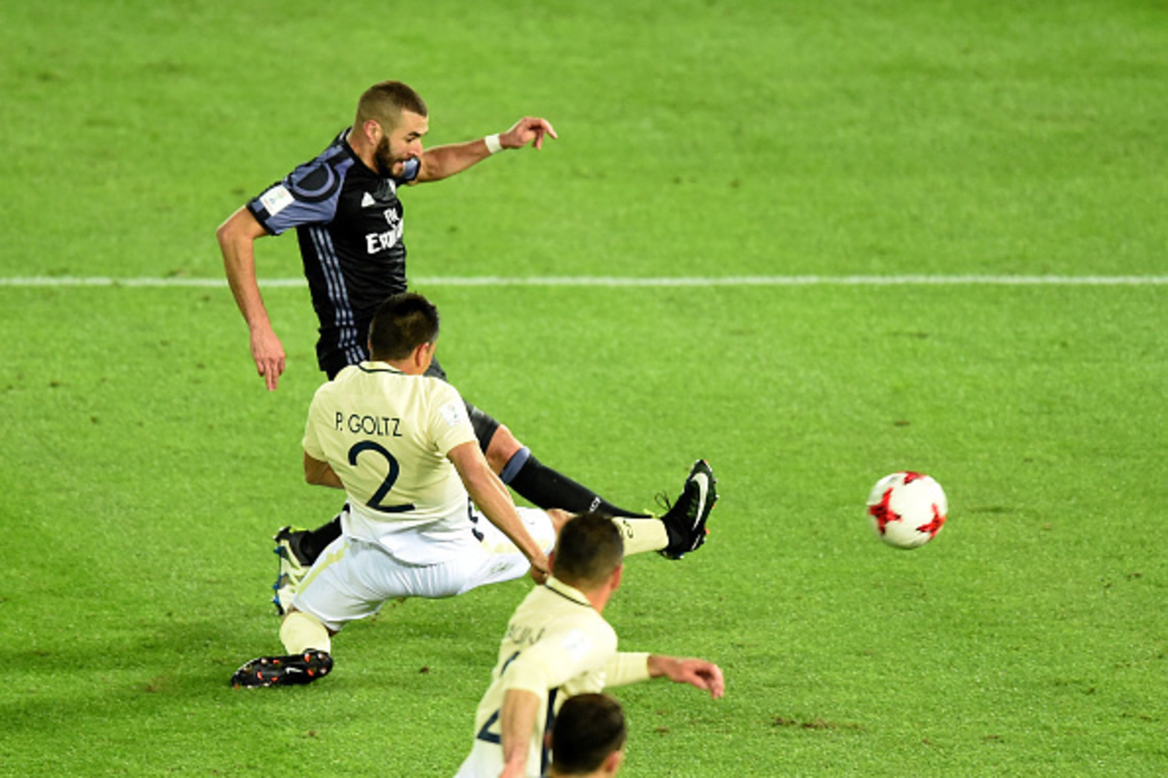 Real Madrid's forward Karim Benzema (top) scores a goal as he battles with Club America's defender Paolo Goltz (#2) during the Club World Cup semi-final football match between Club America of Mexico and Real Madrid of Spain at Yokohama International stadi