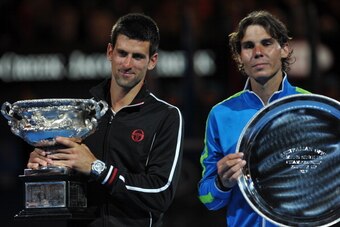 Novak Djokovic of Serbia (L) holds the trophy as he celebrates after victory in his men's singles final match against Rafael Nadal of Spain (R) on the twelfth day of the Australian Open tennis tournament in Melbourne early January 30, 2012.  Djokovic won 