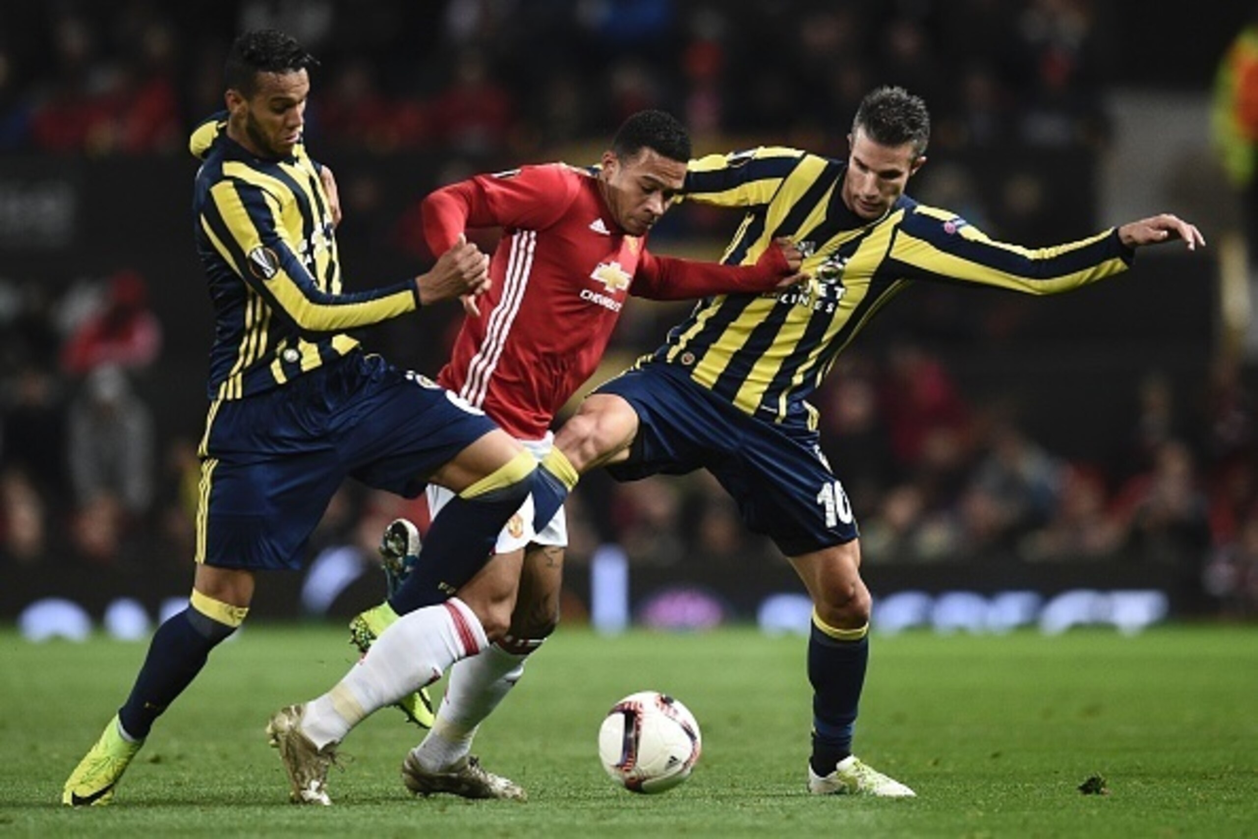Manchester United's Dutch midfielder Memphis Depay (C) rips the shirt of Fenerbahce's Dutch forward Robin van Persie (R) as he struggles between Van Persie and Fenerbahce's Brazilian midfielder Souza (L) during the UEFA Europa League group A football matc