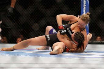 LAS VEGAS, NV - JULY 05:  UFC women's bantamweight champion Ronda Rousey (top) punches Alexis Davis while controlling her body in their UFC women's bantamweight championship fight at UFC 175 inside the Mandalay Bay Events Center on July 5, 2014 in Las Veg
