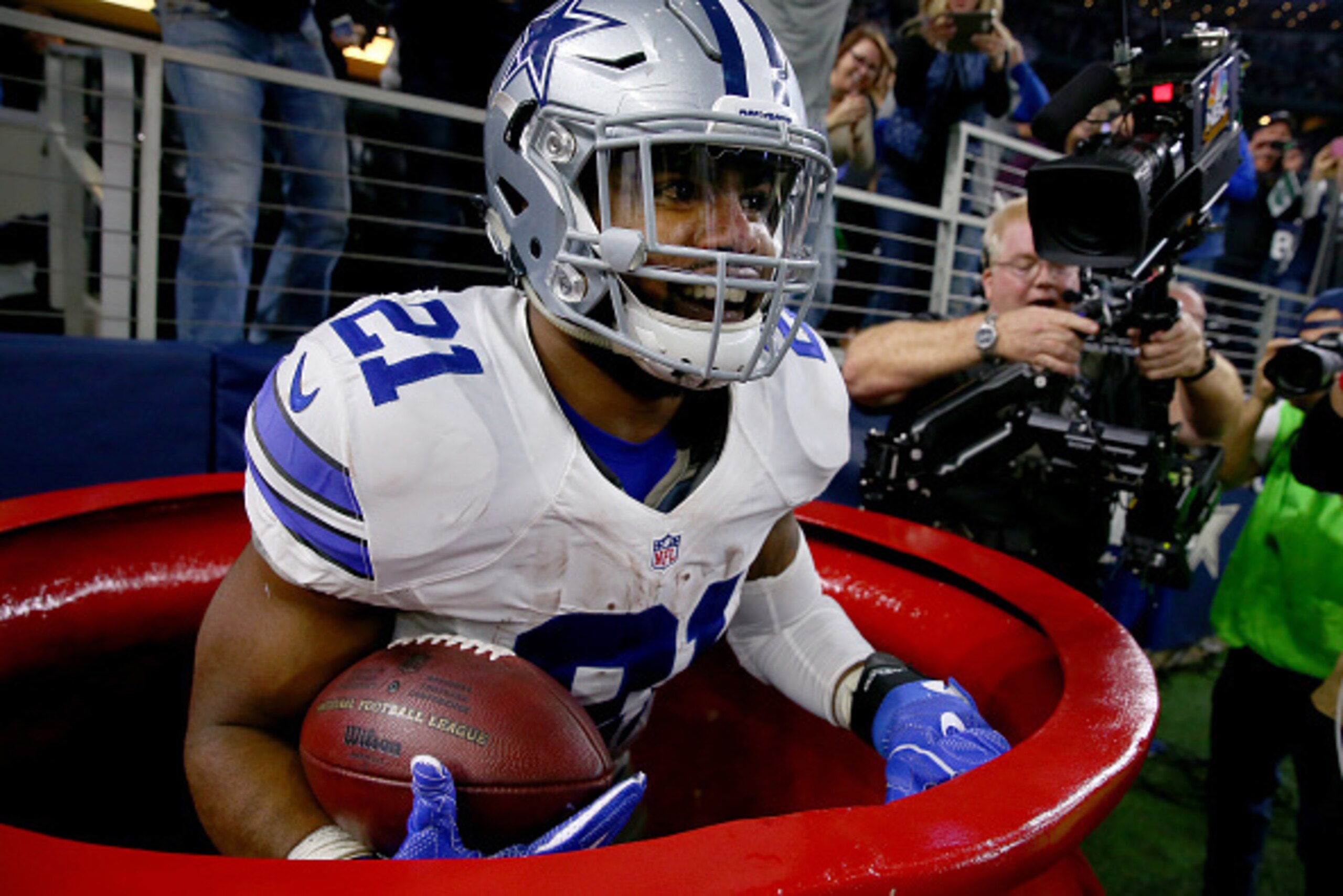 ARLINGTON, TX - DECEMBER 18:  Ezekiel Elliott #21 of the Dallas Cowboys celebrates after scoring a touchdown by jumping into a Salvation Army red kettle during the second quarter against the Tampa Bay Buccaneers at AT&T Stadium on December 18, 2016 in Arl