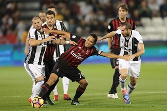 AC Milan's Carlos Bacca (C) vies for the ball with Juventus' Giorgio Chiellini (R) during the Italian Super Cup final match between AC Milan and Juventus in Doha on December 23, 2016. / AFP / KARIM JAAFAR        (Photo credit should read KARIM JAAFAR/AFP/