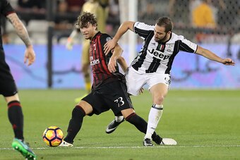 AC Milan's Alessio Romagnoli vies for the ball with Juventus' Gonzalo Higuain during the Italian Super Cup final match between AC Milan and Juventus in Doha on December 23, 2016. / AFP / KARIM JAAFAR        (Photo credit should read KARIM JAAFAR/AFP/Getty