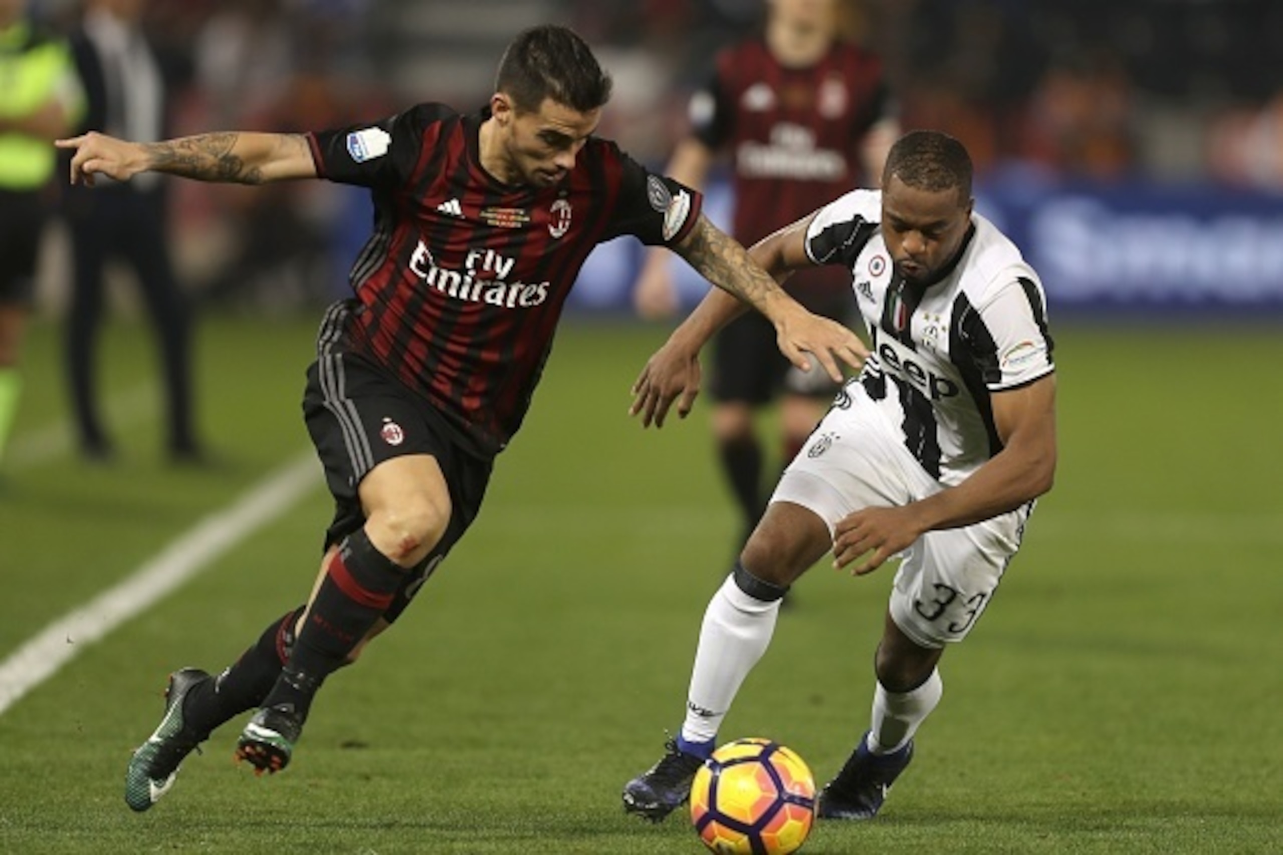 Juventus' Patrice Evra (R) vies for the ball with AC Milan's Fernandez Suso during the Italian Super Cup final match between AC Milan and Juventus in Doha on December 23, 2016. / AFP / KARIM JAAFAR        (Photo credit should read KARIM JAAFAR/AFP/Getty I