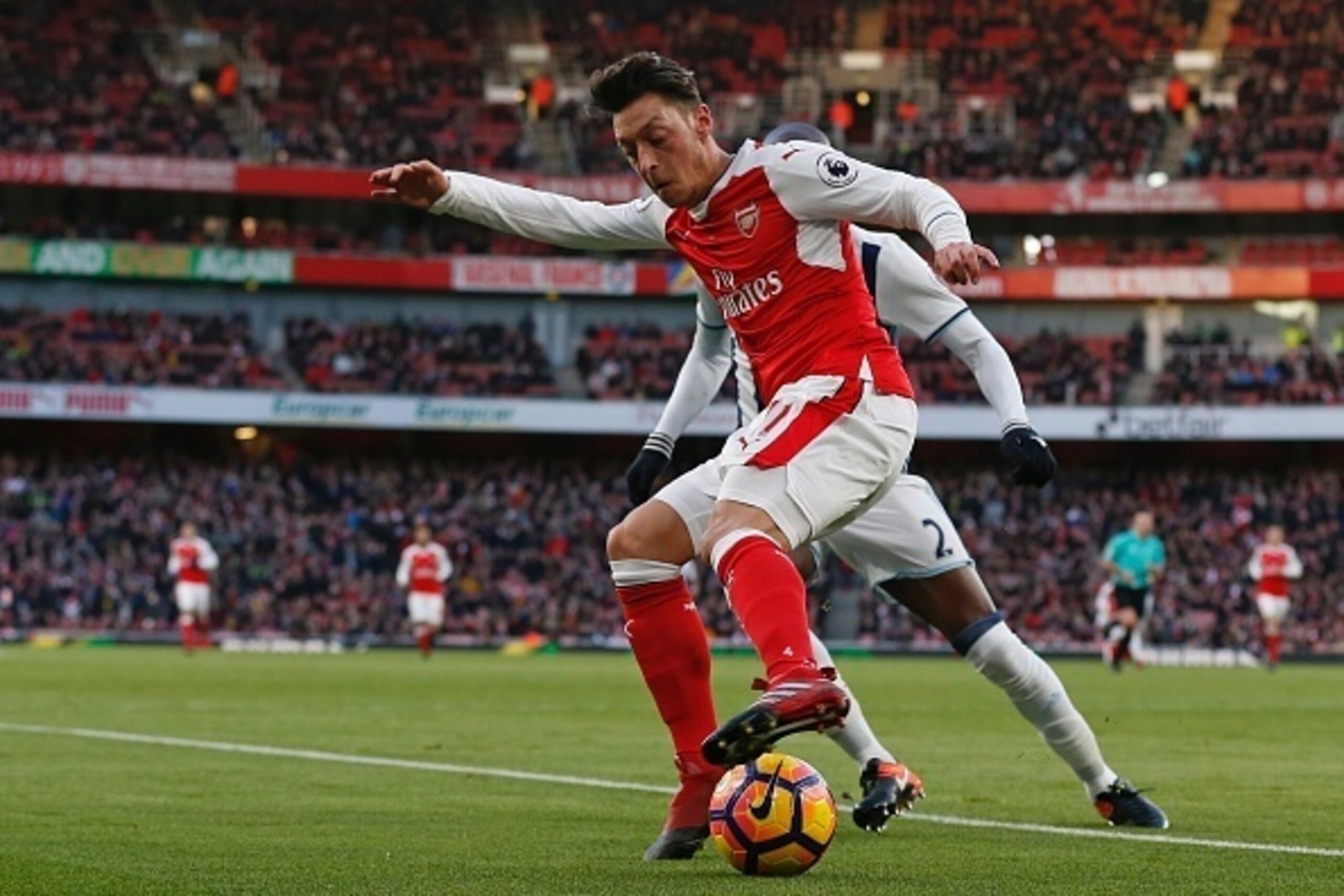 Arsenal's German midfielder Mesut Ozil vies with West Bromwich Albion's French-born Cameroonian defender Allan Nyom (hidden) during the English Premier League football match between Arsenal and West Bromwich Albion at the Emirates Stadium in London on Dec