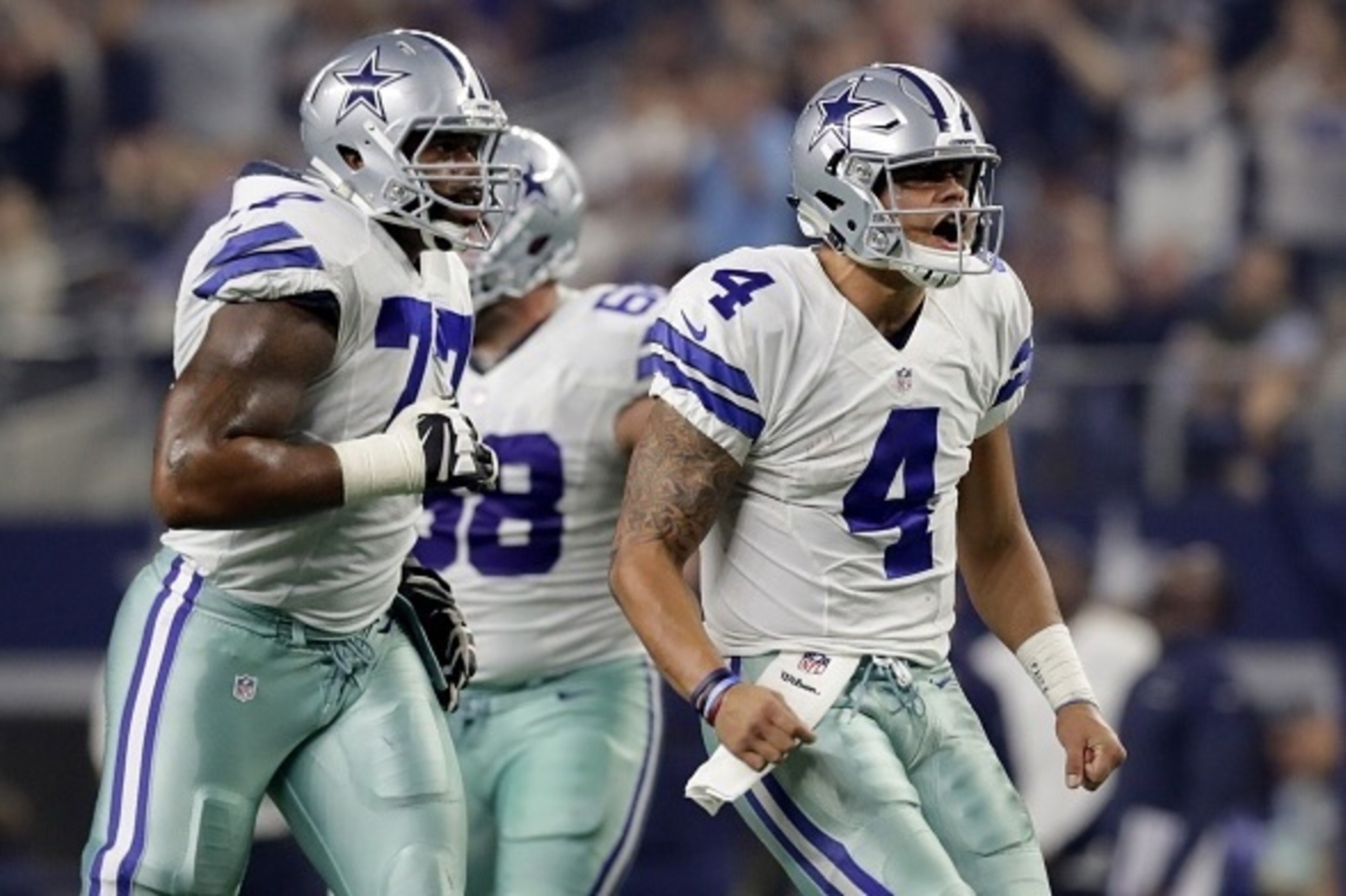 ARLINGTON, TX - DECEMBER 26: Dak Prescott #4 of the Dallas Cowboys reacts as teammate Tyron Smith #77 looks on after throwing a touchdown pass against the Detroit Lions during the first half at AT&T Stadium on December 26, 2016 in Arlington, Texas. (Photo ARLINGTON, TX - DECEMBER 26: Dak Prescott #4 of the Dallas Cowboys reacts as teammate Tyron Smith #77 looks on after throwing a touchdown pass against the Detroit Lions during the first half at AT&T Stadium on December 26, 2016 in Arlington, Texas. (Photo