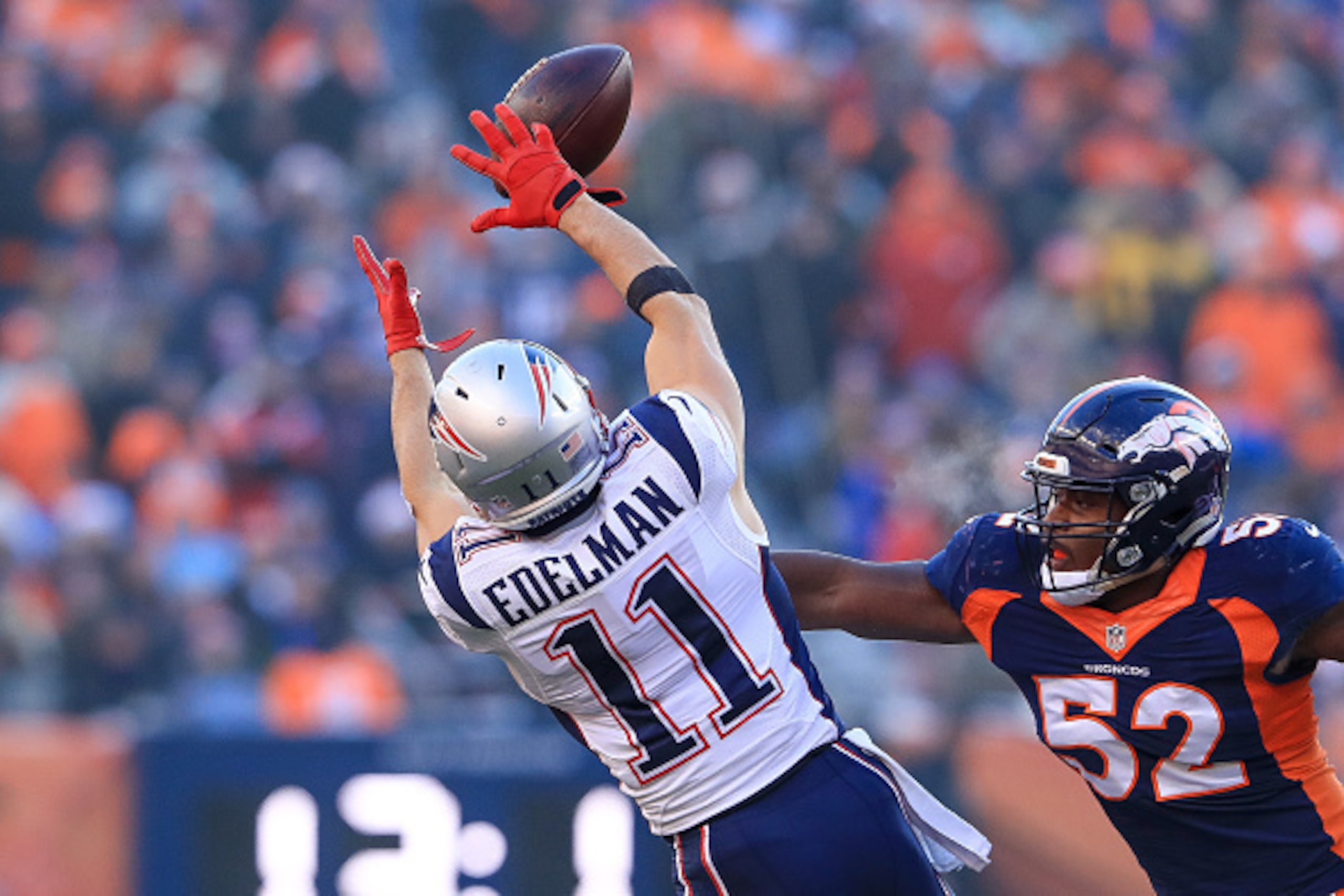 DENVER, CO - DECEMBER 18:  Wide receiver Julian Edelman #11 of the New England Patriots jumps for a reception under coverage by inside linebacker Corey Nelson #52 of the Denver Broncos in the second quarter of a game at Sports Authority Field at Mile High