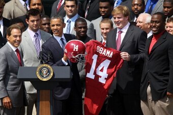 WASHINGTON, DC - APRIL 19:  U.S. President Barack Obama is presented with a jersey and a helmet by defensive lineman Damion Square (R), quarterback A.J. McCarron (2nd L) and offensive lineman Barrett Jones (2nd R) of the University of Alabama Crimson Tide