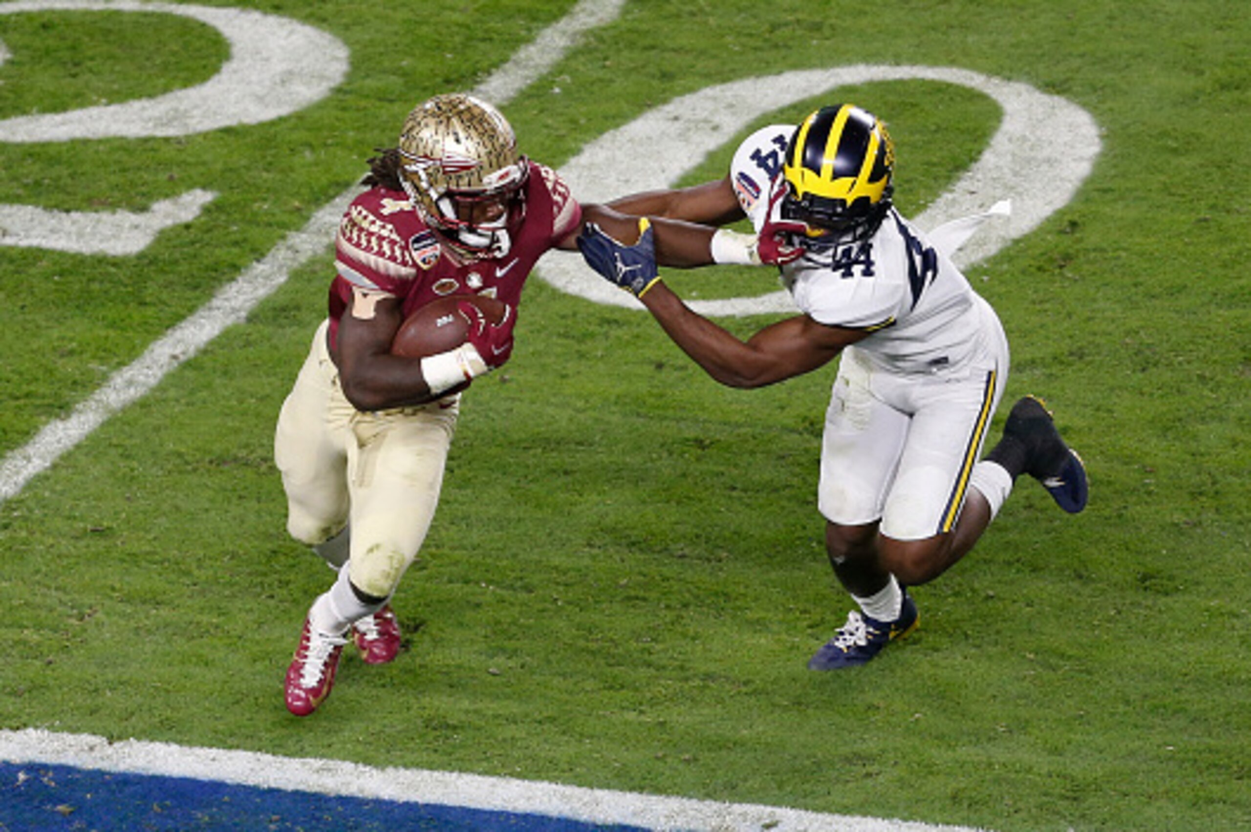 MIAMI GARDENS, FL - DECEMBER 30: Dalvin Cook #4 of the Florida State Seminoles runs past the attempted tackle by Delano Hill #44 of the Michigan Wolverines during the 2016 Capital One Orange Bowl at Hard Rock Stadium on December 30, 2016 in Miami Gardens,
