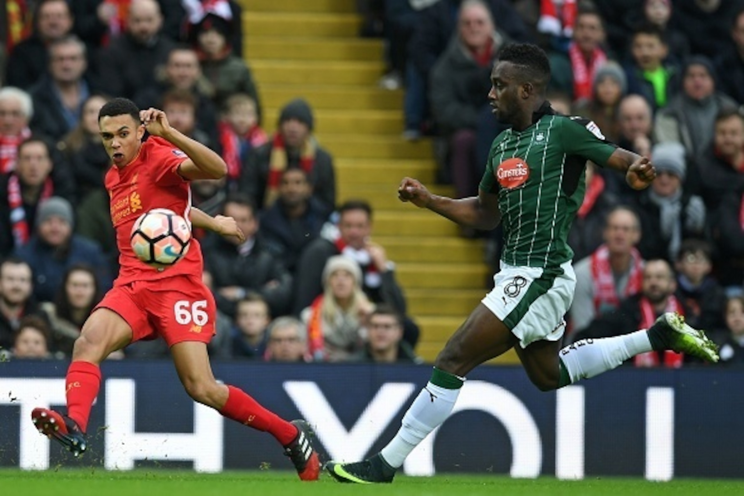 Liverpool's English midfielder Trent Alexander-Arnold (L) crosses the ball as Plymouth's English striker Jordan Slew closes in during the English FA Cup third round football match between Liverpool and Plymouth Argyle at Anfield in Liverpool, north west E