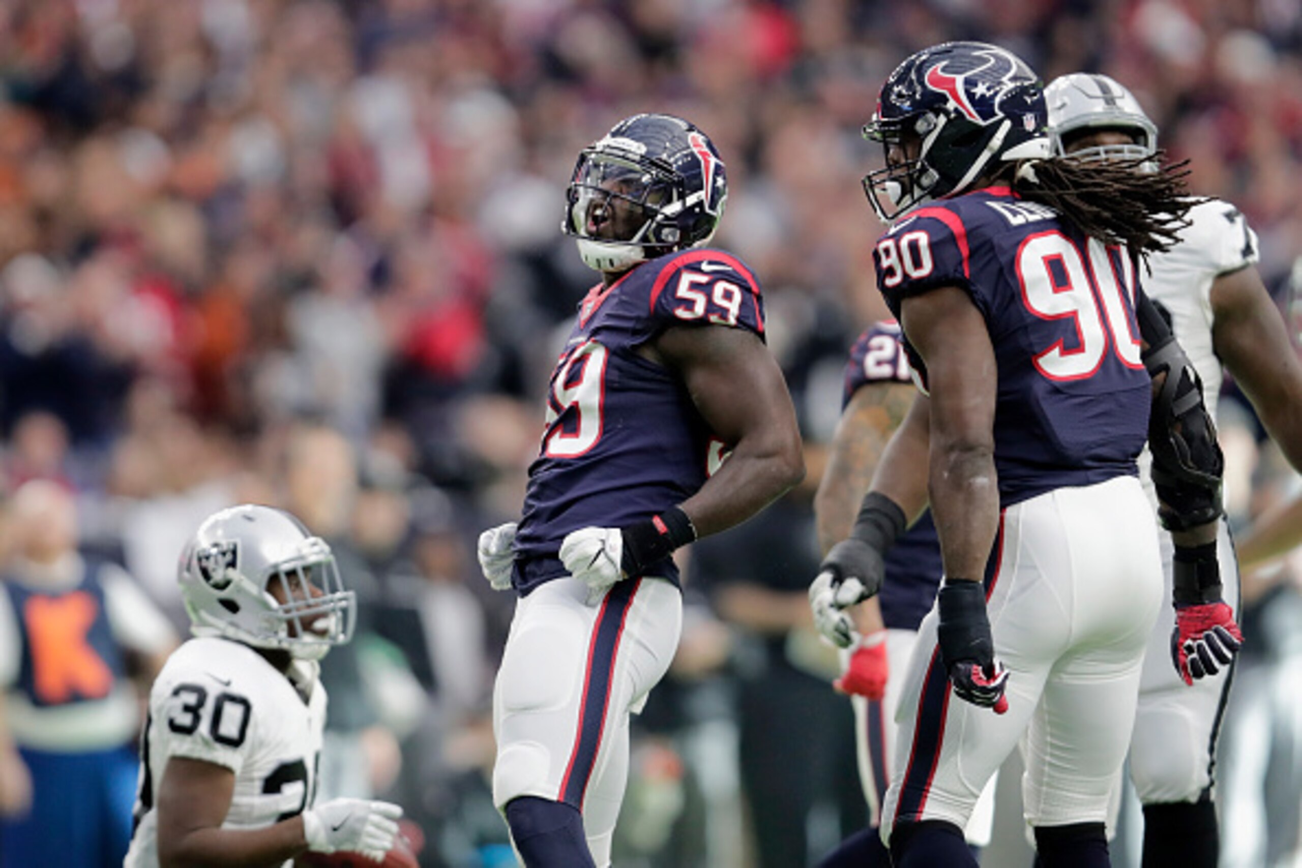 HOUSTON, TX - JANUARY 07: Whitney Mercilus #59 of the Houston Texans and Jadeveon Clowney #90 celebrate after a tackle in the second quarter against the Oakland Raiders at NRG Stadium on January 7, 2017 in Houston, Texas. (Photo by Tim Warner/Getty Images