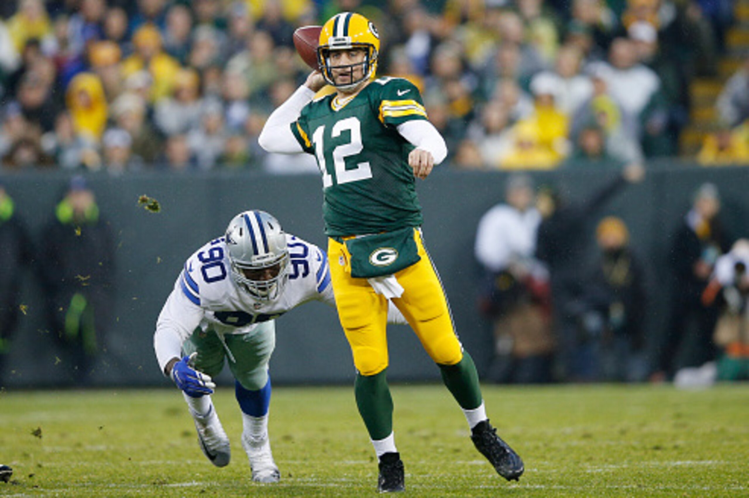 GREEN BAY, WI - DECEMBER 13: Aaron Rodgers #12 of the Green Bay Packers looks to pass while under pressure from DeMarcus Lawrence #90 of the Dallas Cowboys during the game at Lambeau Field on December 13, 2015 in Green Bay, Wisconsin. The Packers defeated
