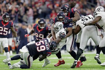 HOUSTON, TX - JANUARY 07: Latavius Murray #28 of the Oakland Raiders is tackled by Whitney Mercilus #59, Antonio Smith #94 and Jadeveon Clowney #90 of the Houston Texans in the AFC Wild Card game at NRG Stadium on January 7, 2017 in Houston, Texas.  (Phot