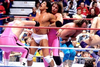 Bret Hart works with tag team partner Jim Neidhart to beat up on Tito Santana.