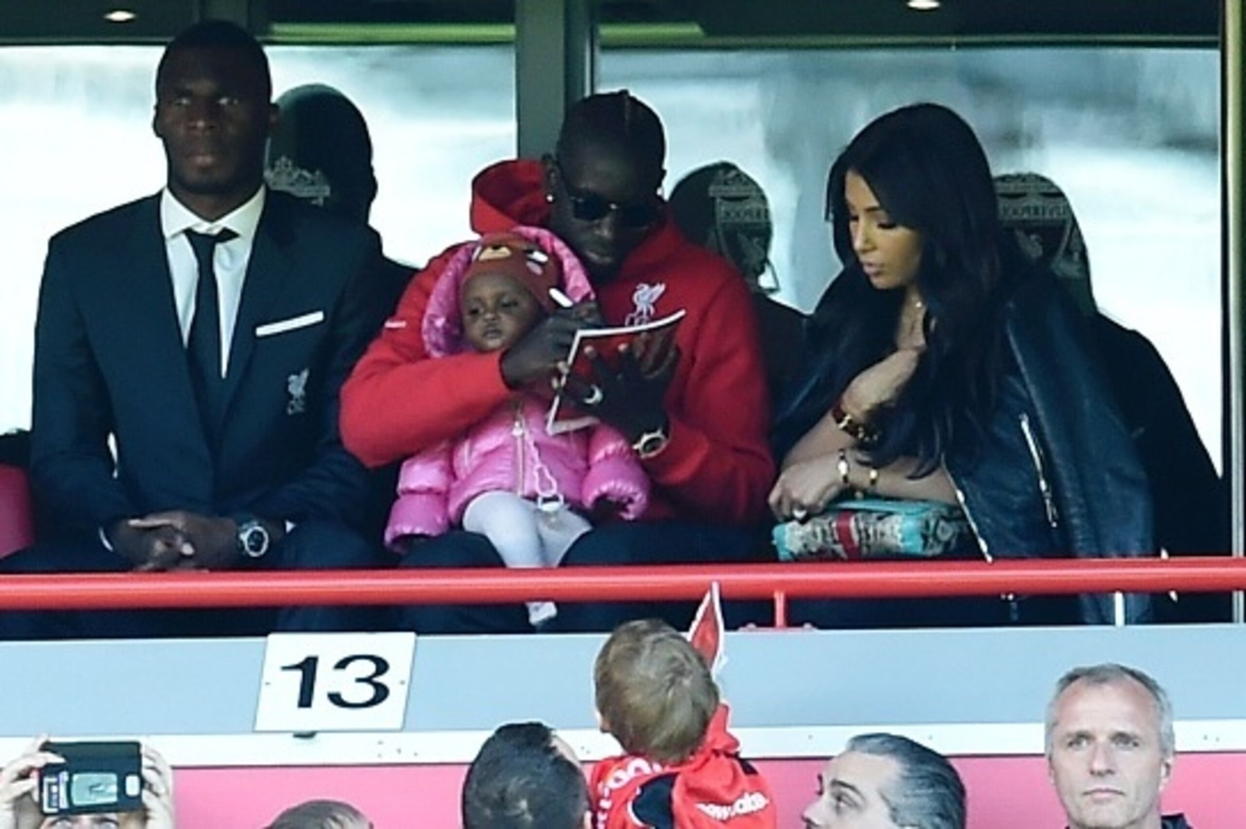 Liverpool's French defender Mamadou Sakho (top C) signs a programme for a fan in the stands sitting next to Liverpool's Zaire-born Belgian striker Christian Benteke (top L) as he attends the English Premier League football match between Liverpool and Newc Liverpool's French defender Mamadou Sakho (top C) signs a programme for a fan in the stands sitting next to Liverpool's Zaire-born Belgian striker Christian Benteke (top L) as he attends the English Premier League football match between Liverpool and Newc