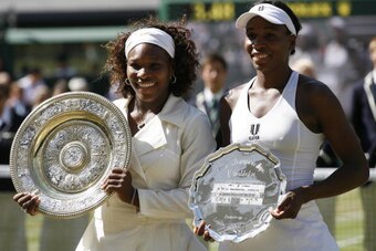 US Serena Williams(L) and US Venus Williams  hold up their trophies after their women's final match on Day 12 at the 2009 Wimbledon tennis championships at the All England Club on July 4, 2009. The event, the third Grand Slam tournament of 2009, runs from