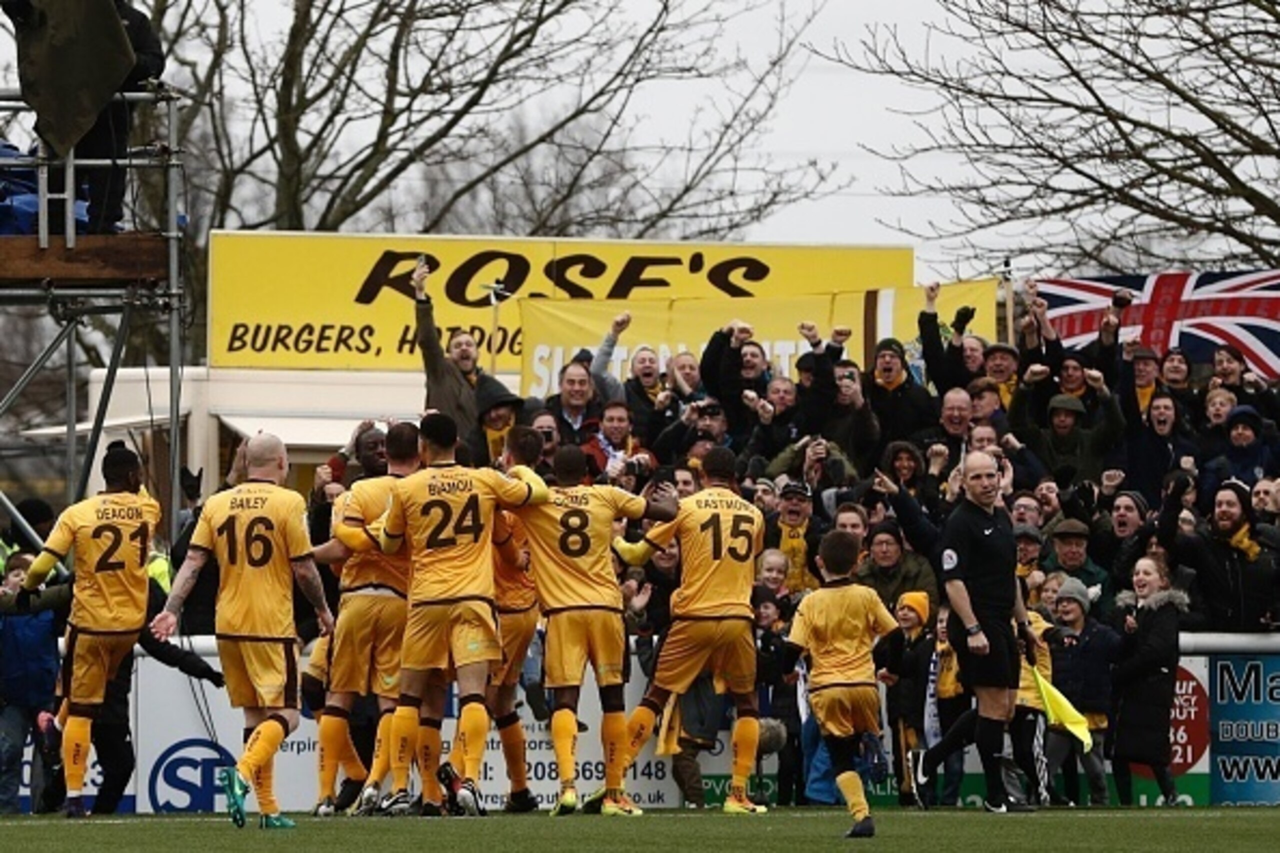 Sutton United's English defender Jamie Collins celebrates with teammates after scoring the opening goal from the penalty spot during the English FA Cup fourth round football match between Sutton United and Leeds United at the Borough Sports Ground in Lond