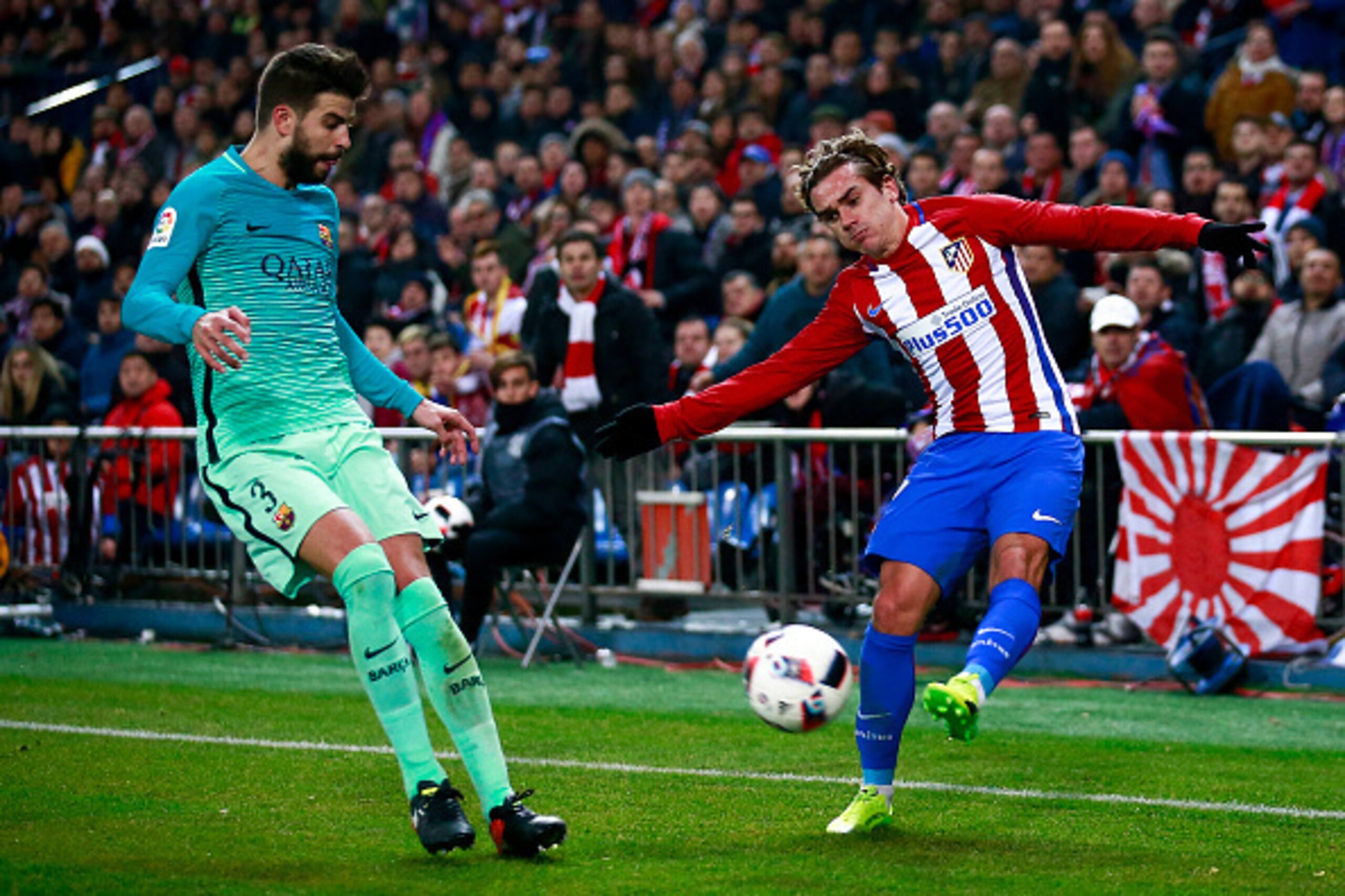 MADRID, SPAIN - FEBRUARY 01: Antoine Griezmann (R) of Atletico de Madrid competes for the ball with Gerard Pique (L) of FC Barcelona during the Copa del Rey semi-final first leg match between Club Atletico de Madrid and FC Barcelona at Estadio Vicente Cal