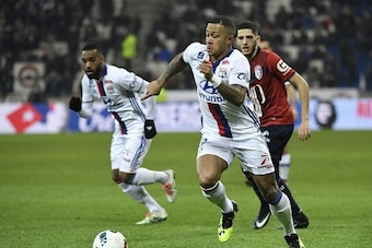 Lyon's Dutch forward Memphis Depay (C) runs with the ball next to Lyon's French forward Alexandre Lacazette (L) and Lille's French forward Yassine Benzia (R) during the French L1 football match Olympique Lyonnais (OL) against Lille (LOSC) on January 28, 2