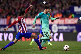 Atletico Madrid's Montenegrin defender Stefan Savic (L) tackles Barcelona's Argentinian forward Lionel Messi during the Spanish Copa del Rey (King's Cup) semi final first leg football match Club Atletico de Madrid vs FC Barcelona at the Vicente Calderon s