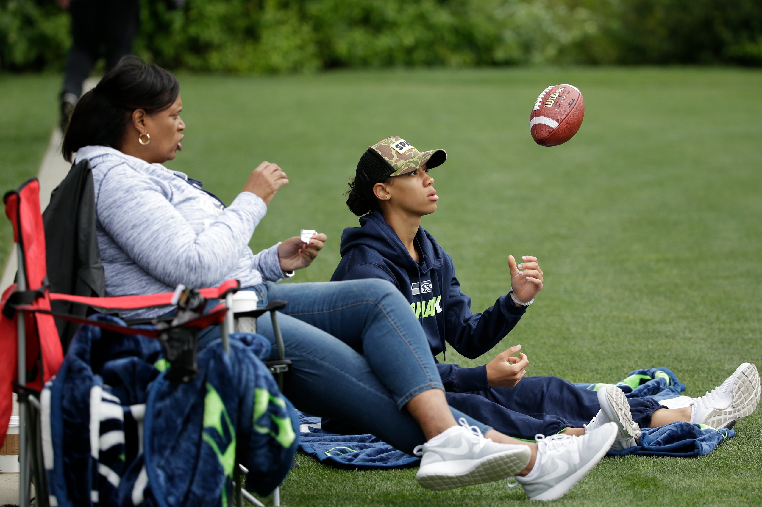 Anna Wilson flips a football as she watches her brother Russell at the Seahawks' 2016 training camp with their mother, Tammy Wilson.