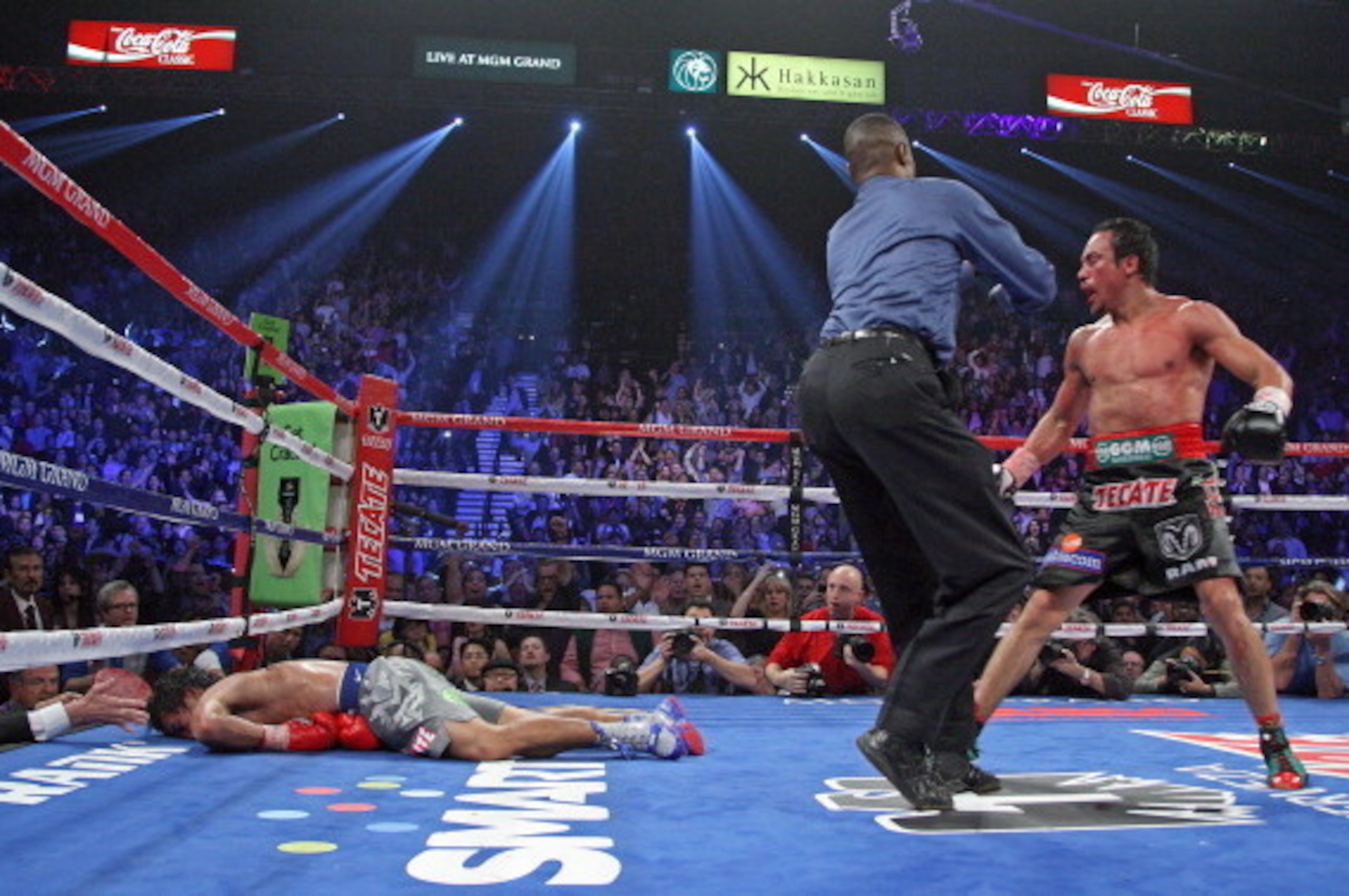 Referee Kenny Bayless (C) holds back Juan Manuel Marquez (R) as Manny Pacquiao (L) lies face down on the mat after being knocked out by Juan Manuel Marquez on December 8, 2012, at the MGM Grand Garden in Las Vegas, Nevada.  AFP PHOTO / John Gurzinski     