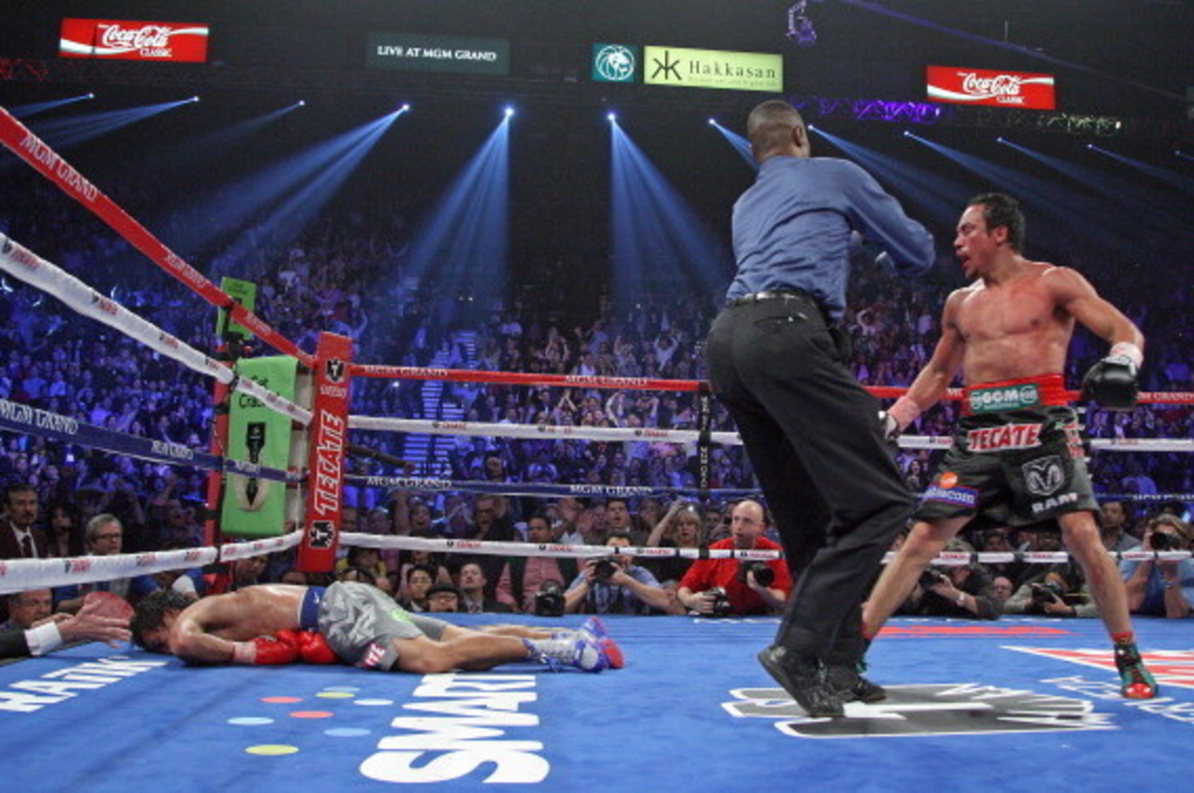 Referee Kenny Bayless (C) holds back Juan Manuel Marquez (R) as Manny Pacquiao (L) lies face down on the mat after being knocked out by Juan Manuel Marquez on December 8, 2012, at the MGM Grand Garden in Las Vegas, Nevada.  AFP PHOTO / John Gurzinski     