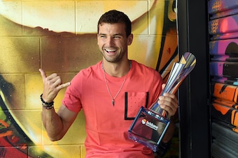 Grigor Dimitrov of Bulgaria poses with his winning trophy in front of graffiti following his men's singles final against Japan's Kei Nishikori at the Brisbane International tennis tournament in Brisbane on January 9, 2017. / AFP / SAEED KHAN / IMAGE RESTR