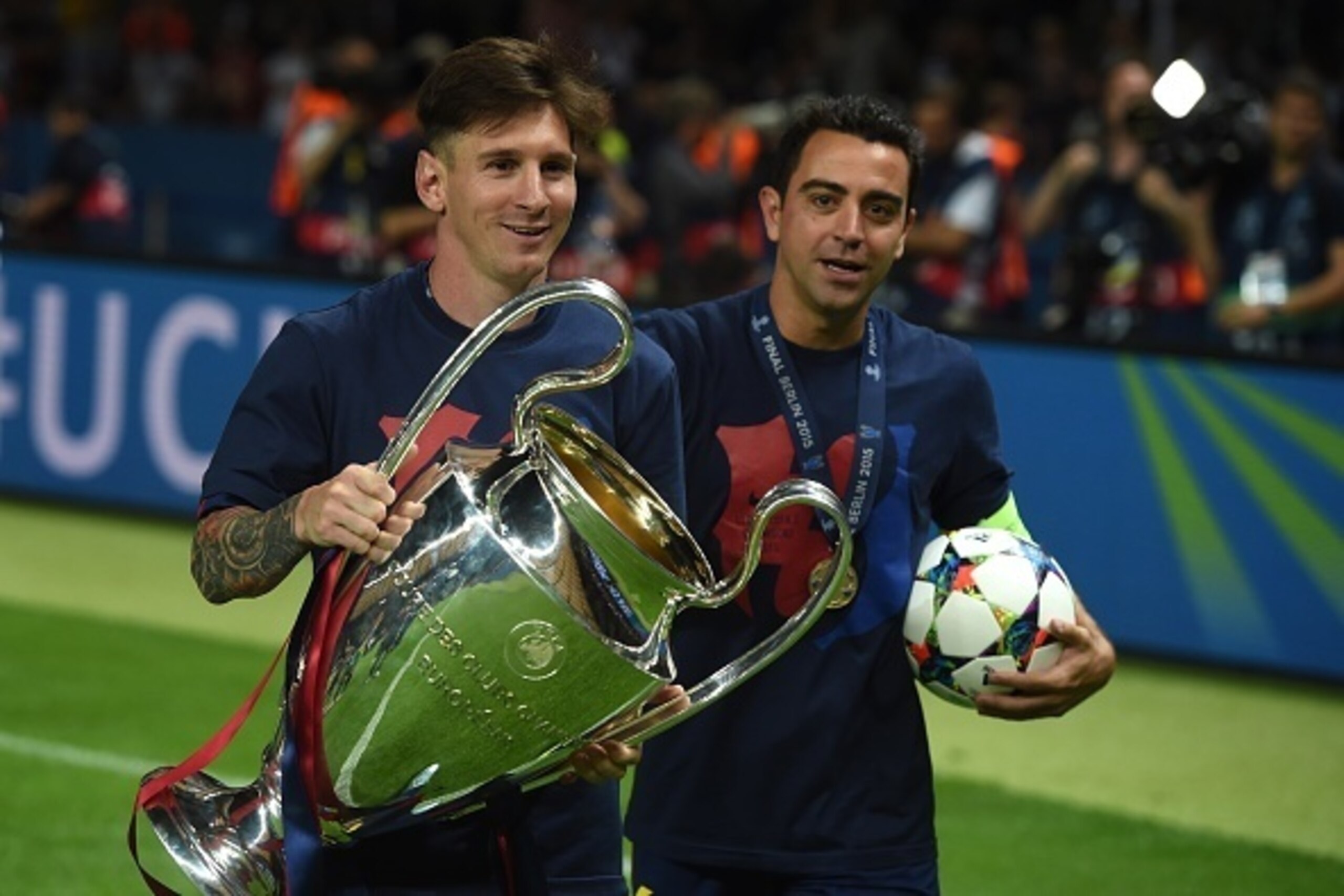 Barcelona's midfielder Xavi Hernandez (R) and Barcelona's Argentinian forward Lionel Messi celebrate with the trophy after the UEFA Champions League Final football match between Juventus and FC Barcelona at the Olympic Stadium in Berlin on June 6, 2015. F
