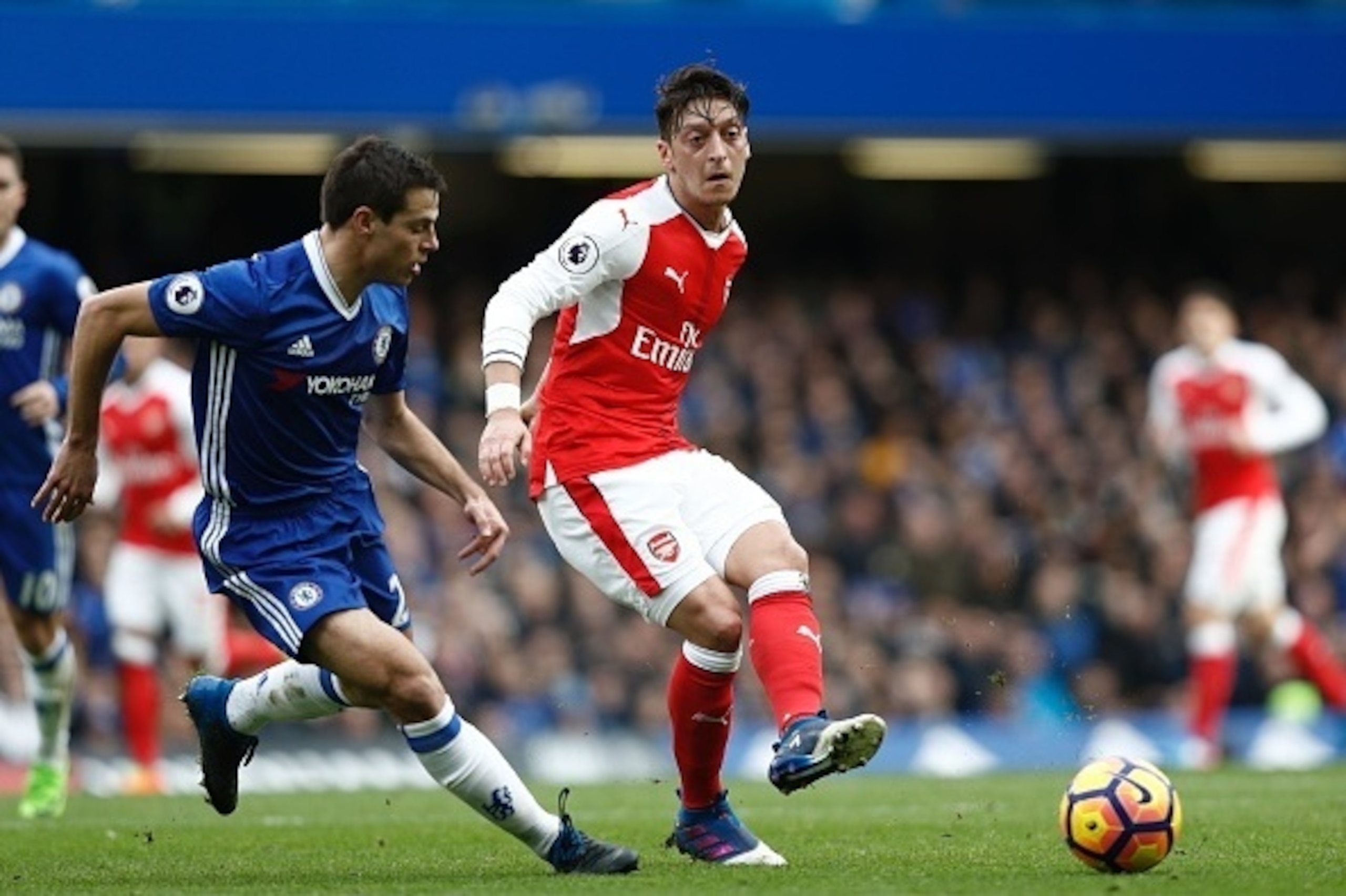 Arsenal's German midfielder Mesut Ozil (R) plays the ball during the English Premier League football match between Chelsea and Arsenal at Stamford Bridge in London on February 4, 2017. / AFP / Adrian DENNIS / RESTRICTED TO EDITORIAL USE. No use with unaut