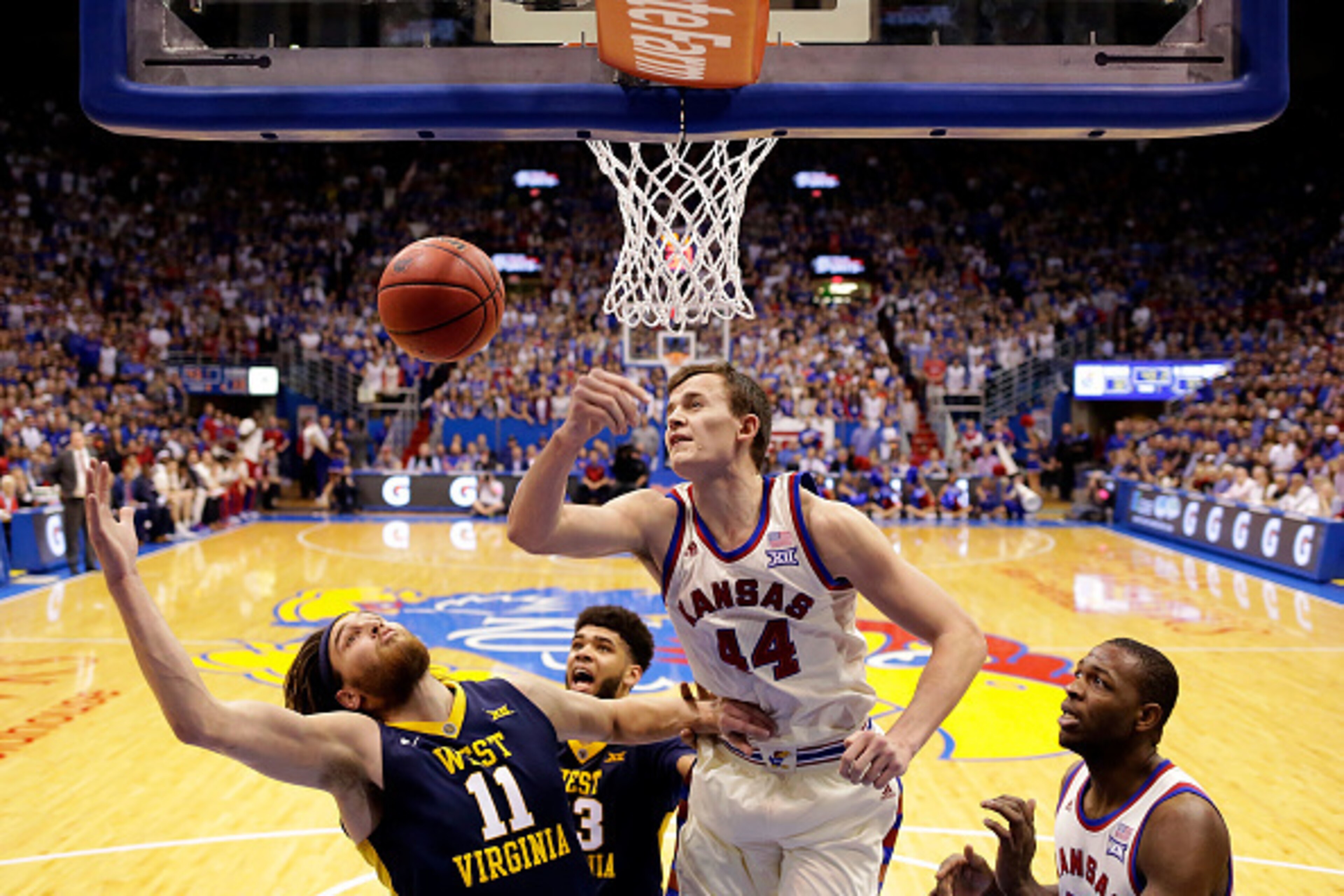 LAWRENCE, KS - FEBRUARY 13:  Mitch Lightfoot #44 of the Kansas Jayhawks and battles Nathan Adrian #11 of the West Virginia Mountaineers for a rebound during the game at Allen Fieldhouse on February 13, 2017 in Lawrence, Kansas.  (Photo by Jamie Squire/Get