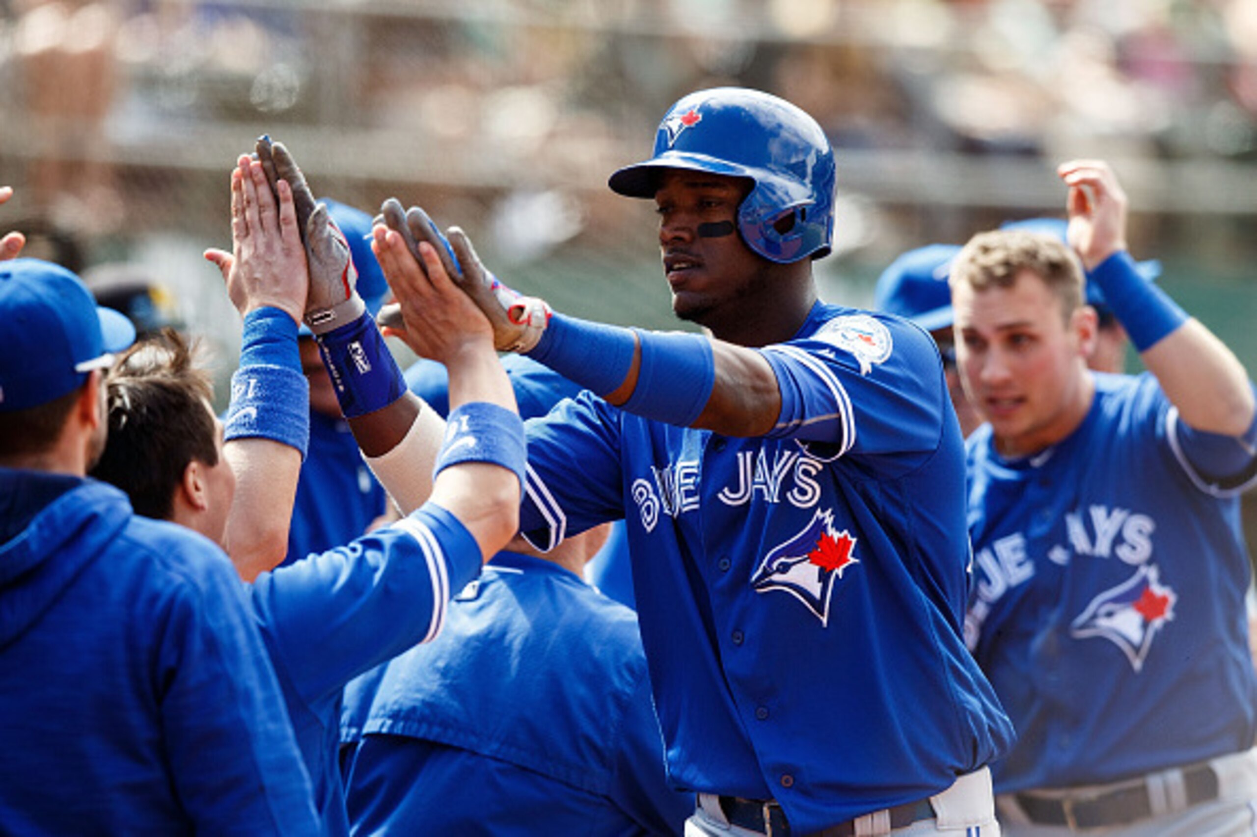 OAKLAND, CA - JULY 17:  Junior Lake #48 of the Toronto Blue Jays and Andy Burns #1 celebrate with teammates in the dugout after both scored runs on a double by Josh Donaldson (not pictured) during the ninth inning against the Oakland Athletics at the Oakl