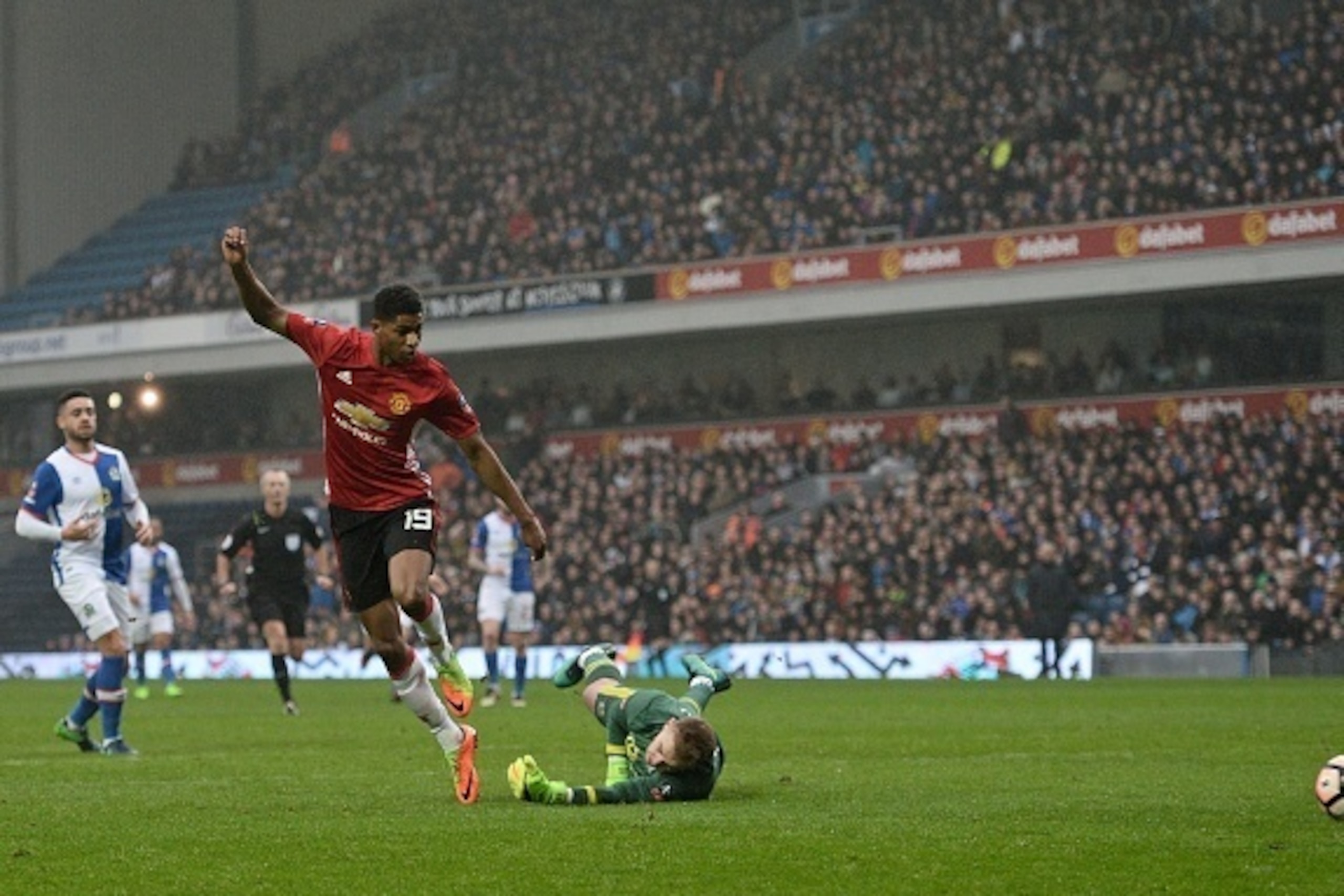 Manchester United's English striker Marcus Rashford (L) scores past Blackburn Rovers' English goalkeeper Jason Steele during the English FA Cup fifth round football match between Blackburn Rovers and Manchester United at Ewood Park in Blackburn, north wes