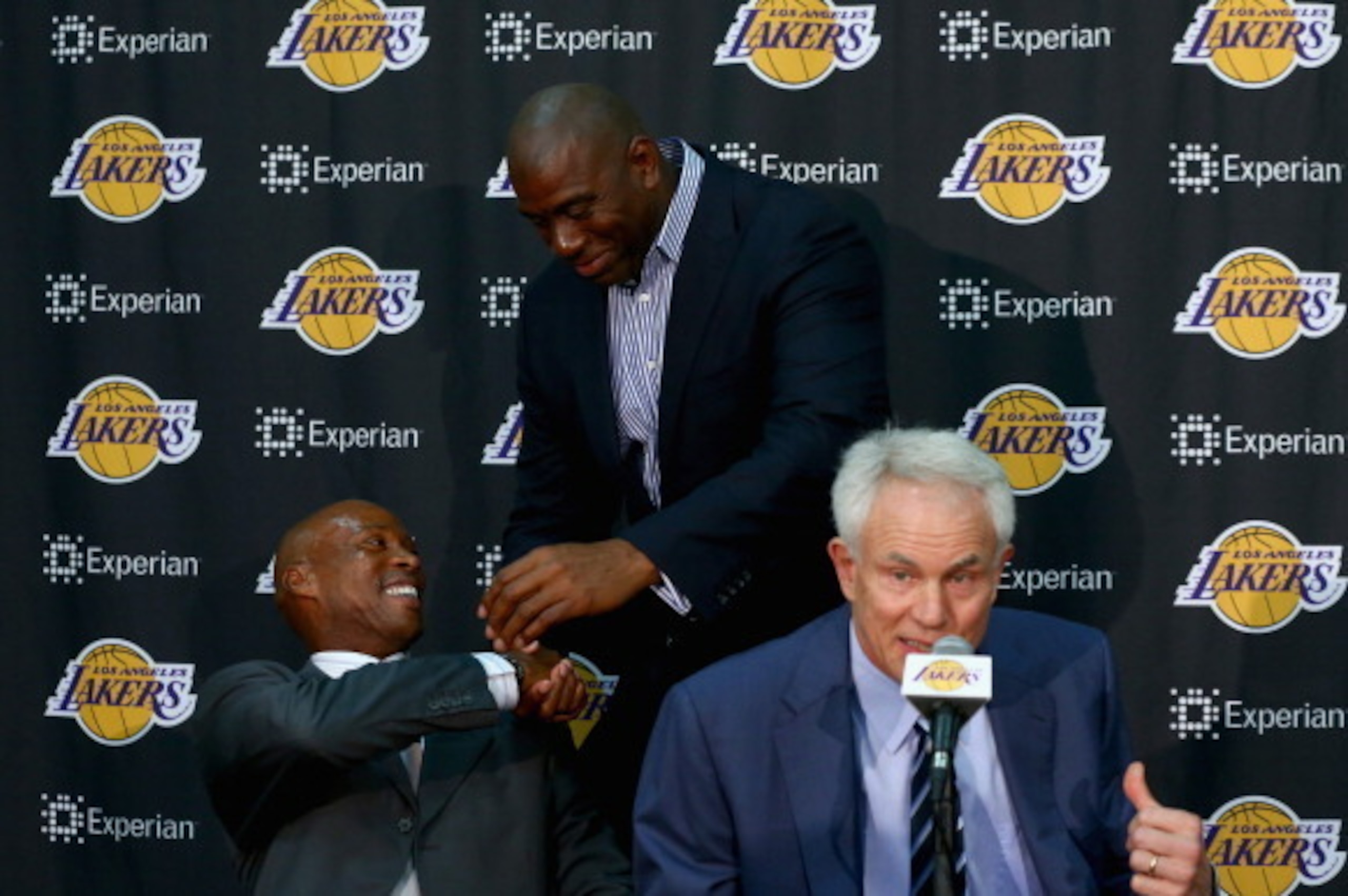 EL SEGUNDO, CA - JULY 29:  (L-R) Byron Scott shakes hands with Earvin 'Magic' Johnson, as Los Angeles Lakers general manager Mitch Kupchak addresses the media during a press conference to introduce Byron Scott as the new head coach of the Los Angeles Lake