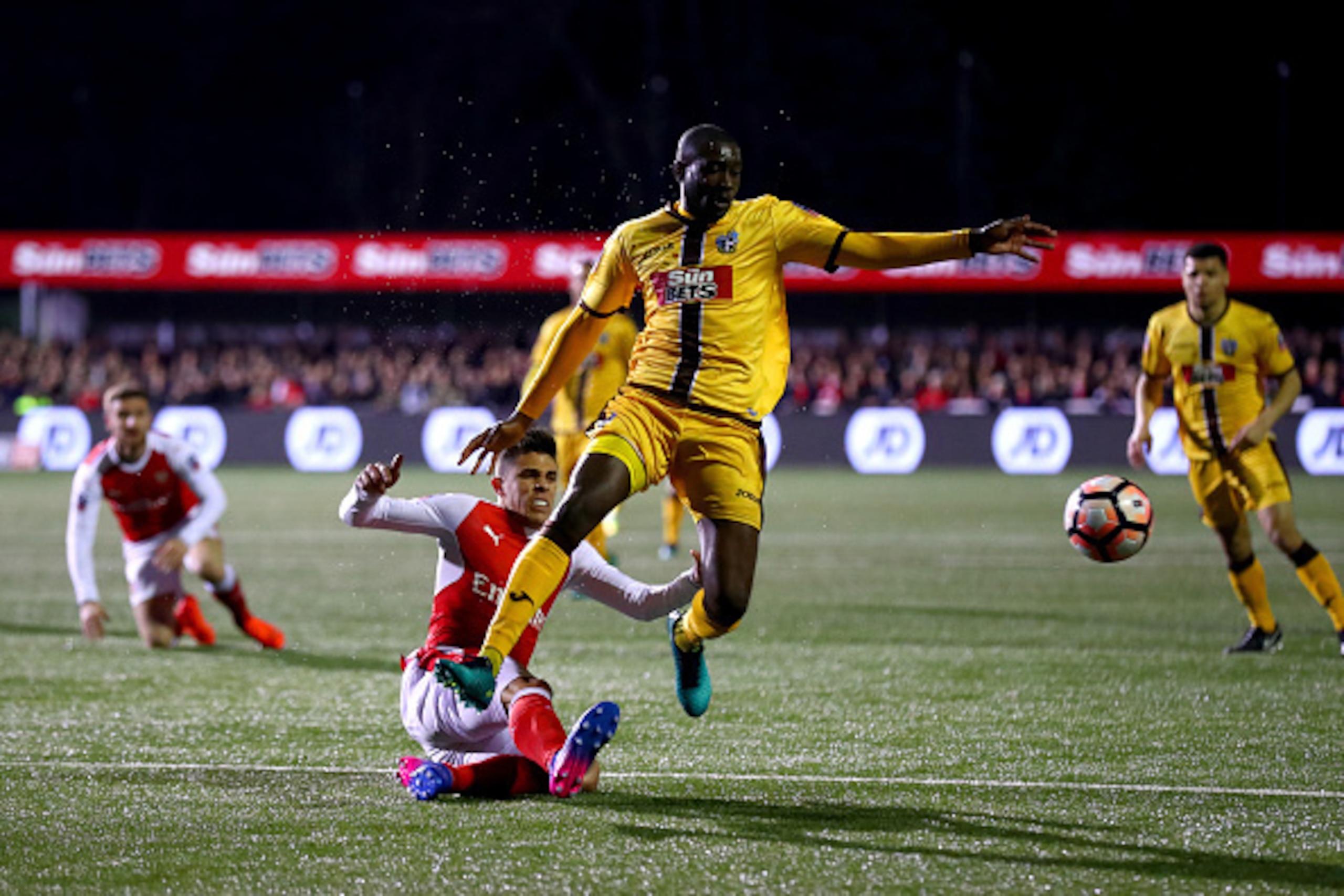 SUTTON, GREATER LONDON - FEBRUARY 20: Gabriel Paulista of Arsenal clears the ball under pressure from Bedsente Gomis of Sutton United during the Emirates FA Cup fifth round match between Sutton United and Arsenal on February 20, 2017 in Sutton, Greater L SUTTON, GREATER LONDON - FEBRUARY 20: Gabriel Paulista of Arsenal clears the ball under pressure from Bedsente Gomis of Sutton United during the Emirates FA Cup fifth round match between Sutton United and Arsenal on February 20, 2017 in Sutton, Greater L