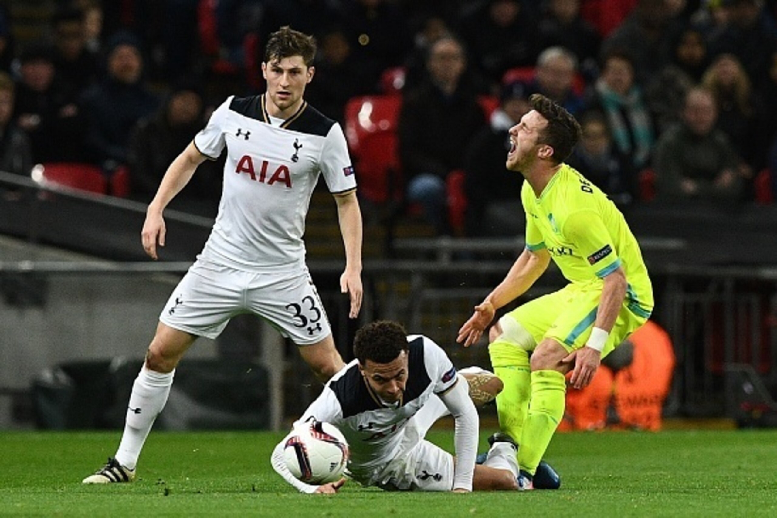 Tottenham Hotspur's English midfielder Dele Alli (C) challenges Gent's Belgian midfielder Brecht Dejaegere (R) and earns a straight red card sending off during the UEFA Europa League Round of 32 second-leg football match between Tottenham Hotspur and KAA 