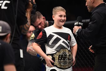 Cody Garbrandt (back) places the UFC title belt around Maddux Maple's waist after defeating Dominick Cruz in their UFC bantamweight championship bout during the UFC 207 event at T-Mobile Arena on December 30, 2016, in Las Vegas.