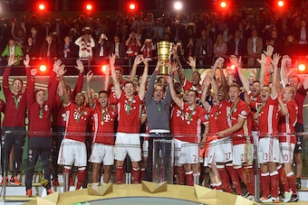 Bayern Munich's players and Bayern Munich's Spanish head coach Pep Guardiola (C) celebrate with the trophy after defeating Dortmund in the penalty shootout of the German Cup (DFB Pokal) final football match Bayern Munich vs Borussia Dortmund at the Olympi