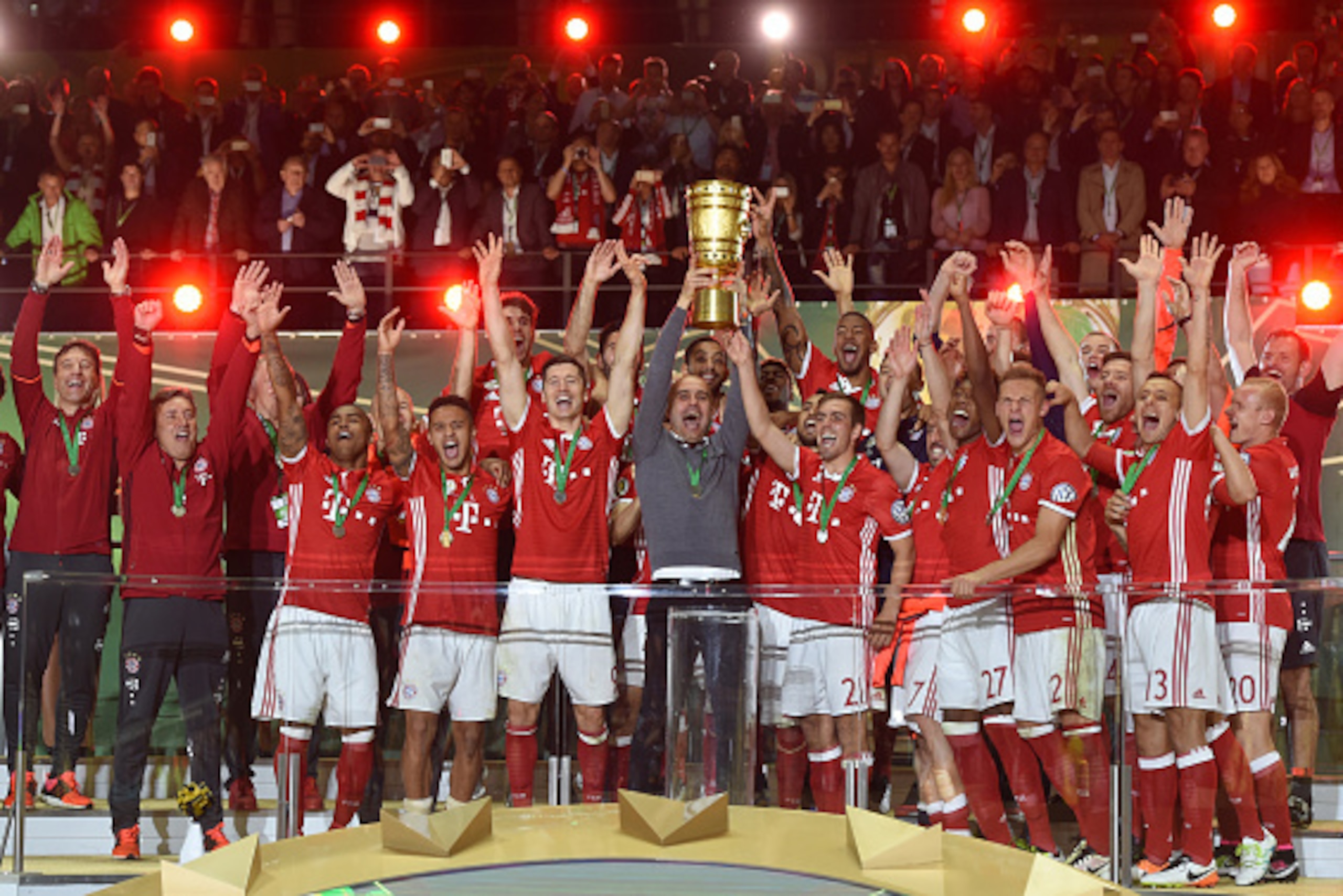 Bayern Munich's players and Bayern Munich's Spanish head coach Pep Guardiola (C) celebrate with the trophy after defeating Dortmund in the penalty shootout of the German Cup (DFB Pokal) final football match Bayern Munich vs Borussia Dortmund at the Olympi