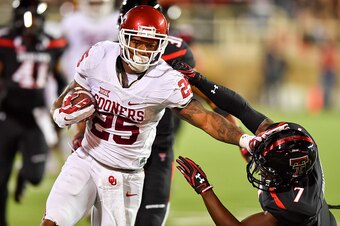 LUBBOCK, TX - OCTOBER 22: Joe Mixon #25 of the Oklahoma Sooners gets past Jah'Shawn Johnson #7 of the Texas Tech Red Raiders during the first half of the game between the Texas Tech Red Raiders and the Oklahoma Sooners on October 22, 2016 at AT&T Jones St