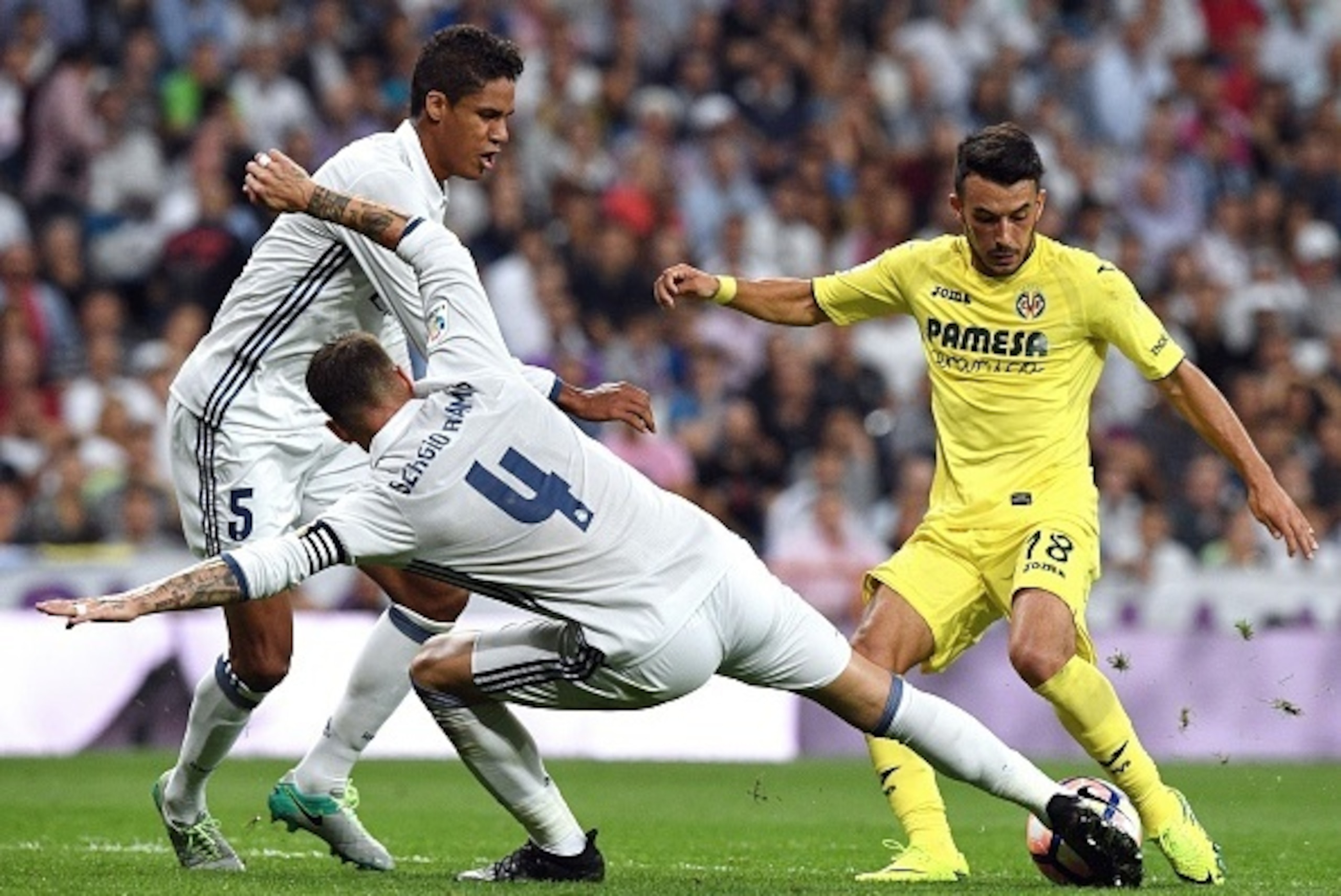 Villarreal's Italian forward Nicola Sansone (R) vies with Real Madrid's French defender Raphael Varane (L) and Real Madrid's defender Sergio Ramos during the Spanish league football match Real Madrid CF vs Villarreal CF at the Santiago Bernabeu stadium in Villarreal's Italian forward Nicola Sansone (R) vies with Real Madrid's French defender Raphael Varane (L) and Real Madrid's defender Sergio Ramos during the Spanish league football match Real Madrid CF vs Villarreal CF at the Santiago Bernabeu stadium in