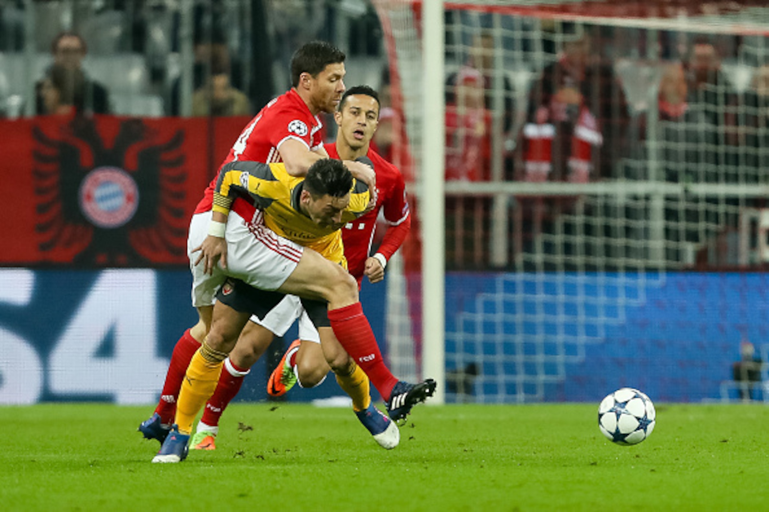MUNICH, GERMANY - FEBRUARY 15: Xabi Alonso of Munich and Mesut Oezil of Arsenal battle for the ball during the UEFA Champions League Round of 16 first leg match between FC Bayern Muenchen and Arsenal FC at Allianz Arena on February 15, 2017 in Munich, Ger