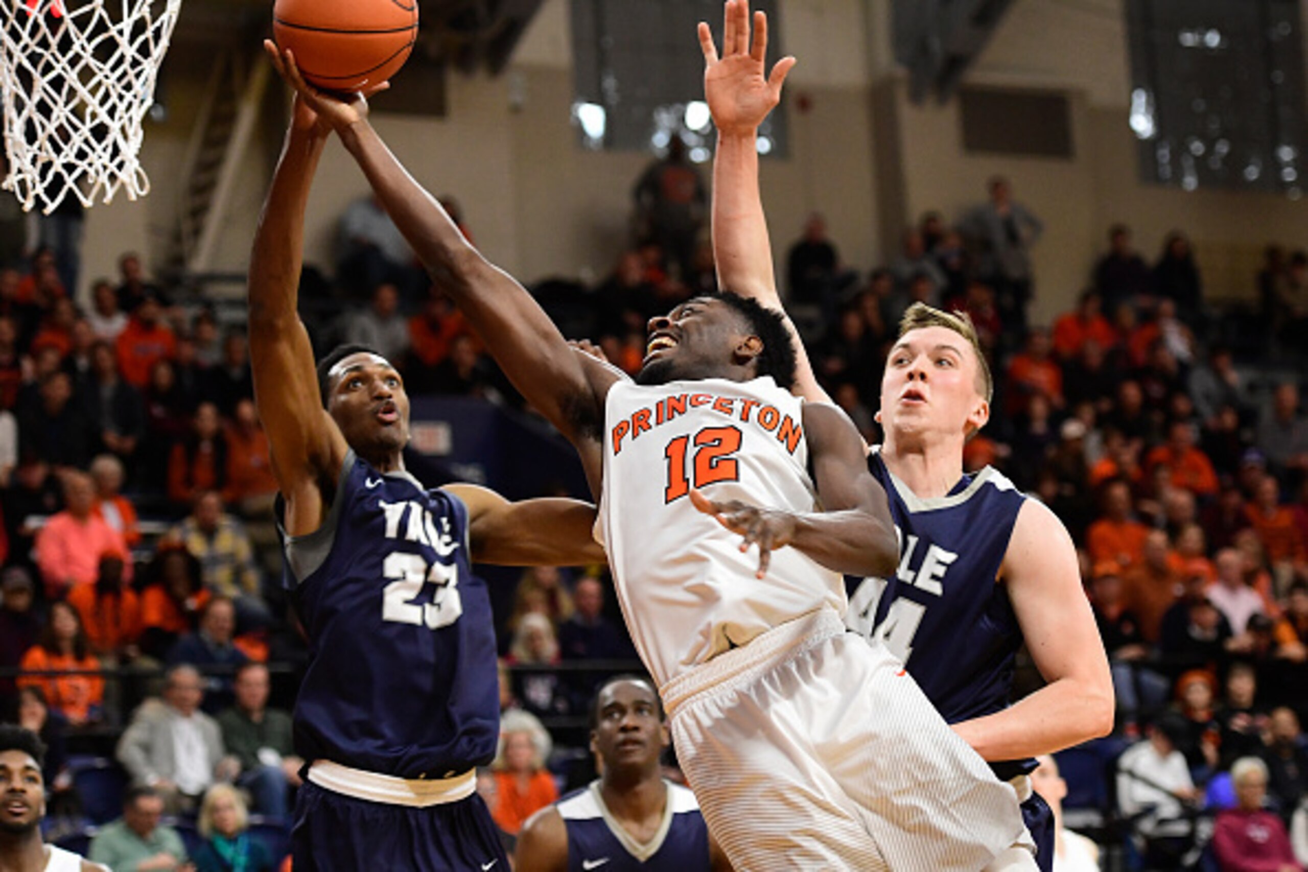 PHILADELPHIA, PA - MARCH 12: Myles Stephens #12 of the Princeton Tigers is fouled on his way to the basket by Jordan Bruner #23 and Sam Downey #44 of the Yale Bulldogs pressuring during the second half of the Ivy League tournament final at The Palestra on