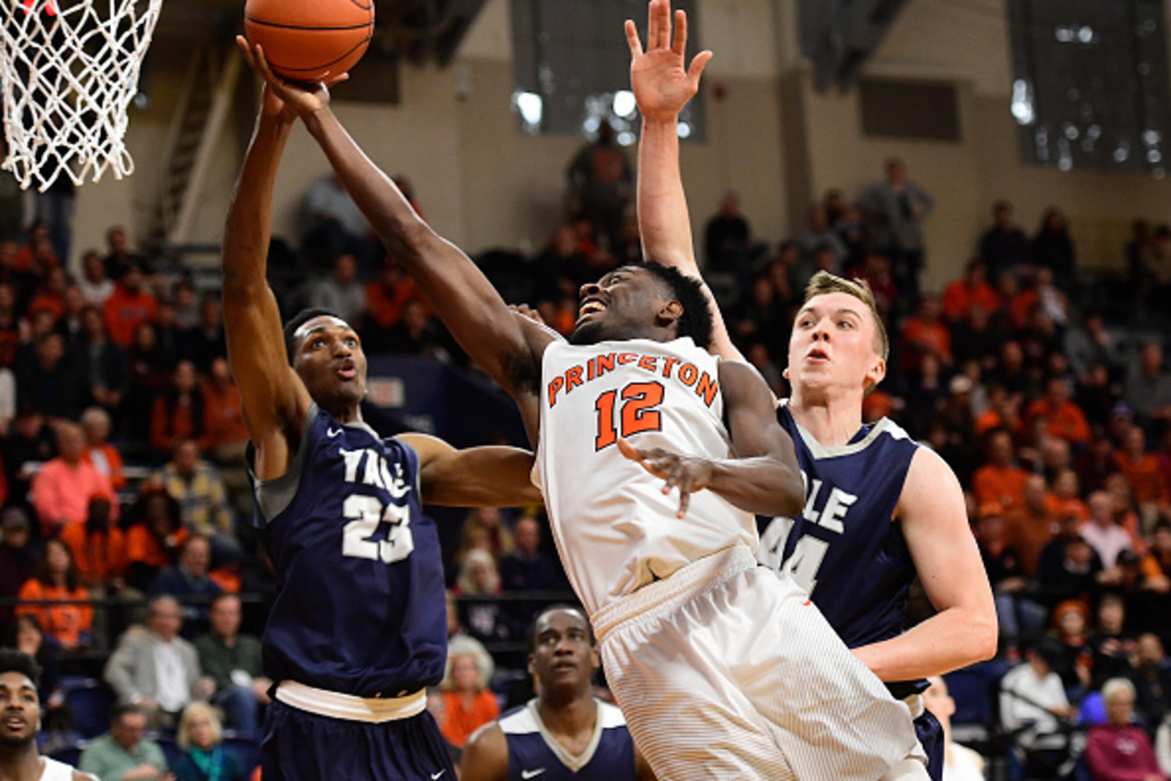 PHILADELPHIA, PA - MARCH 12: Myles Stephens #12 of the Princeton Tigers is fouled on his way to the basket by Jordan Bruner #23 and Sam Downey #44 of the Yale Bulldogs pressuring during the second half of the Ivy League tournament final at The Palestra on