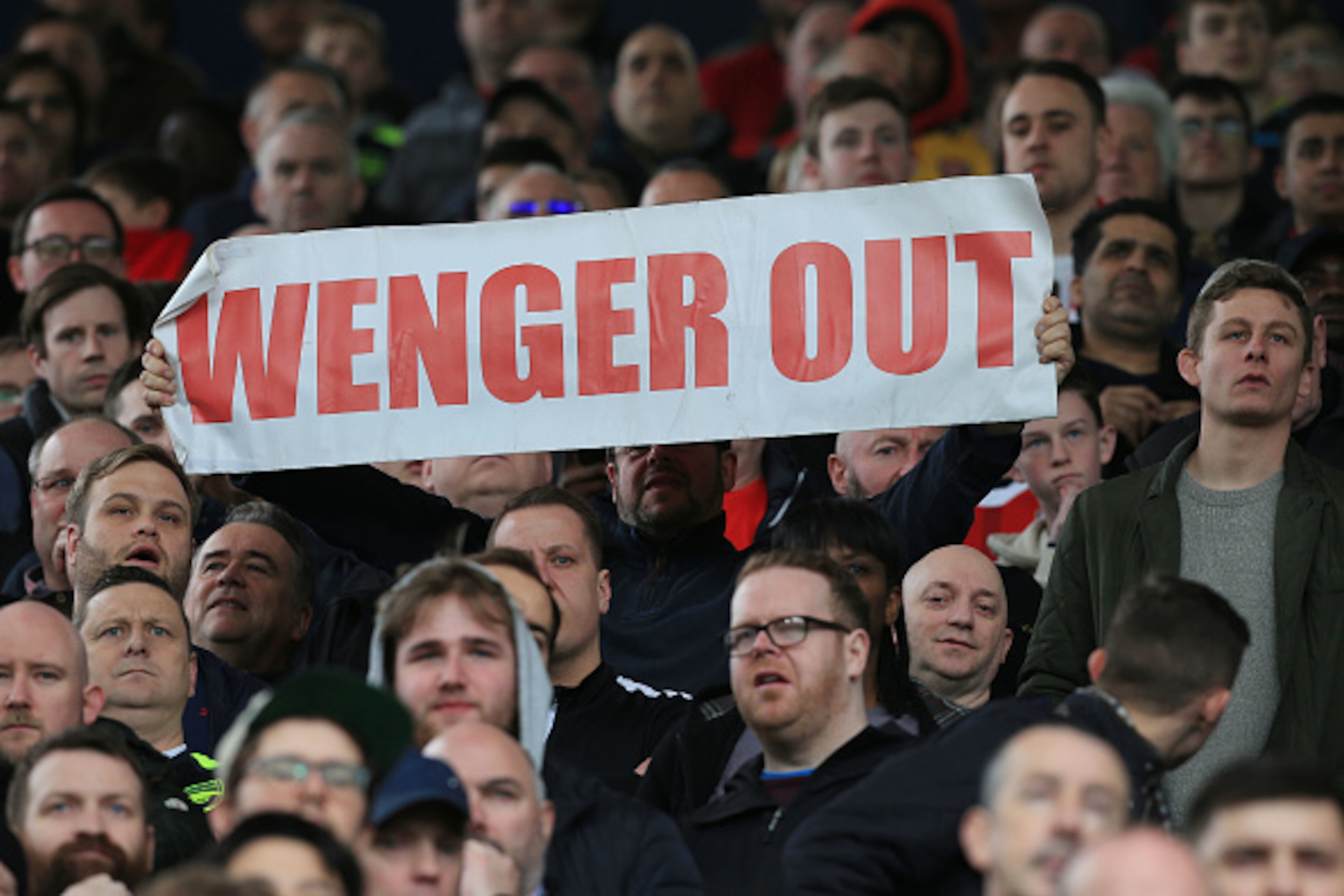 A fan holds up an anti-Arsene Wenger sign during the English Premier League football match between West Bromwich Albion and Arsenal at The Hawthorns stadium in West Bromwich, central England, on March 18, 2017.
 / AFP PHOTO / Lindsey PARNABY / RESTRICTED 