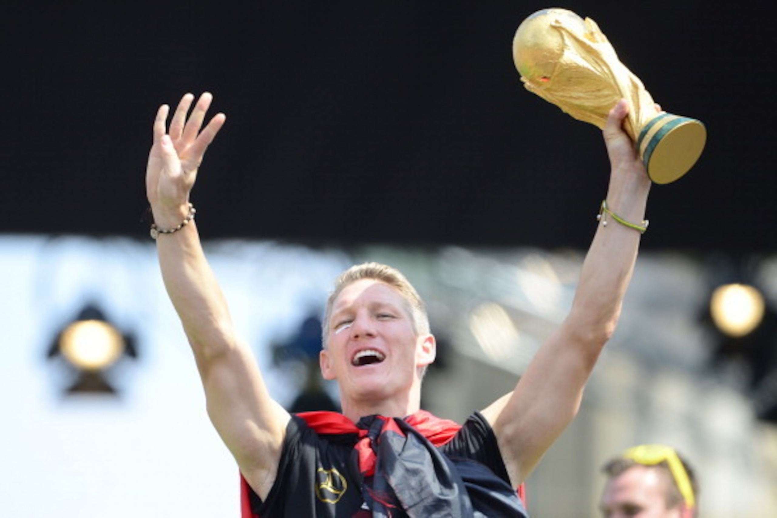 Germany's national football team's midfielder Bastian Schweinsteiger holds the trophy as he celebrates their FIFA World Cup 2014 title at a victory parade in front of fans on July 15, 2014 at Berlin's landmark Brandenburg Gate. Germany won their fourth Wo